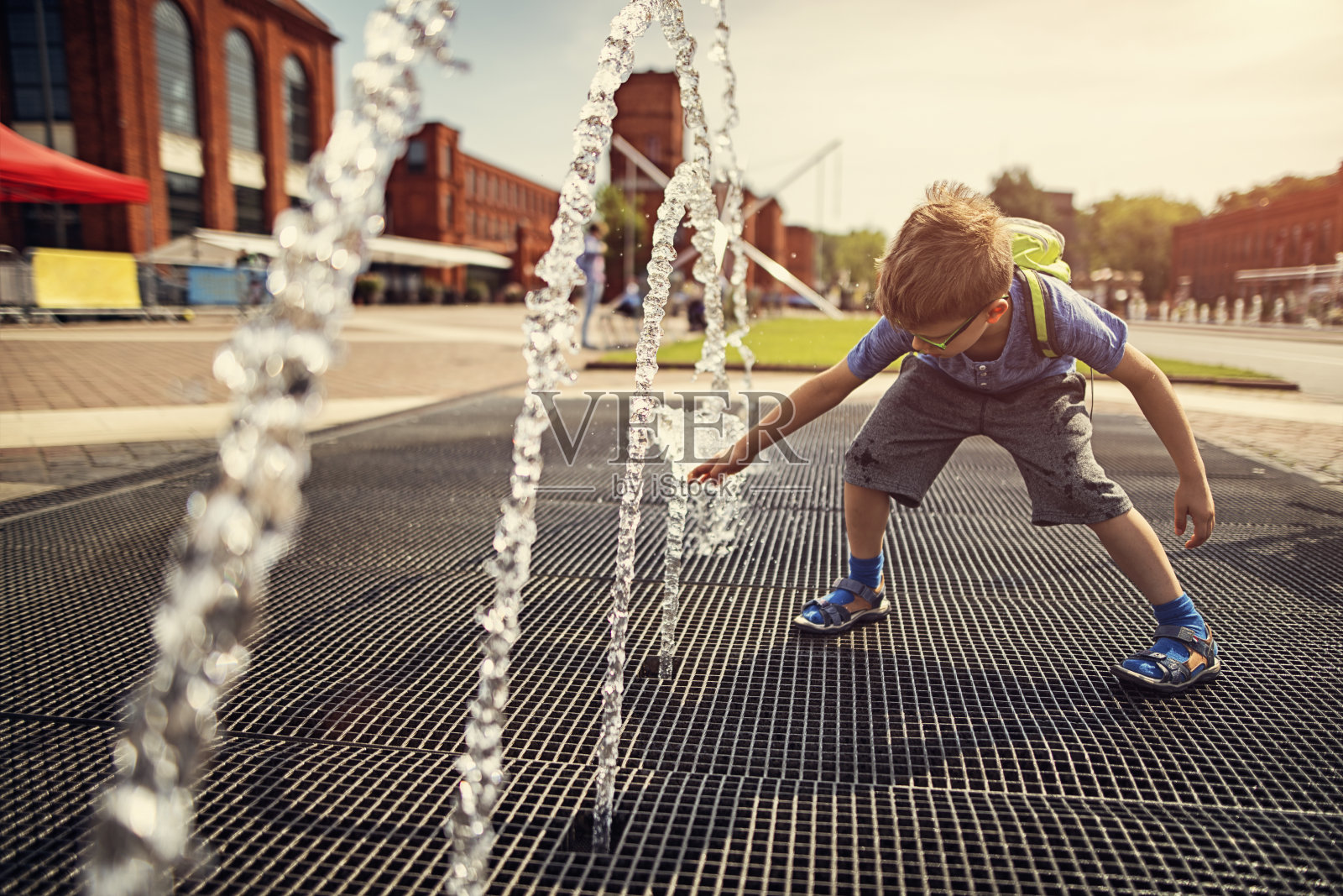 小男孩在一个炎热的夏天玩喷泉。照片摄影图片