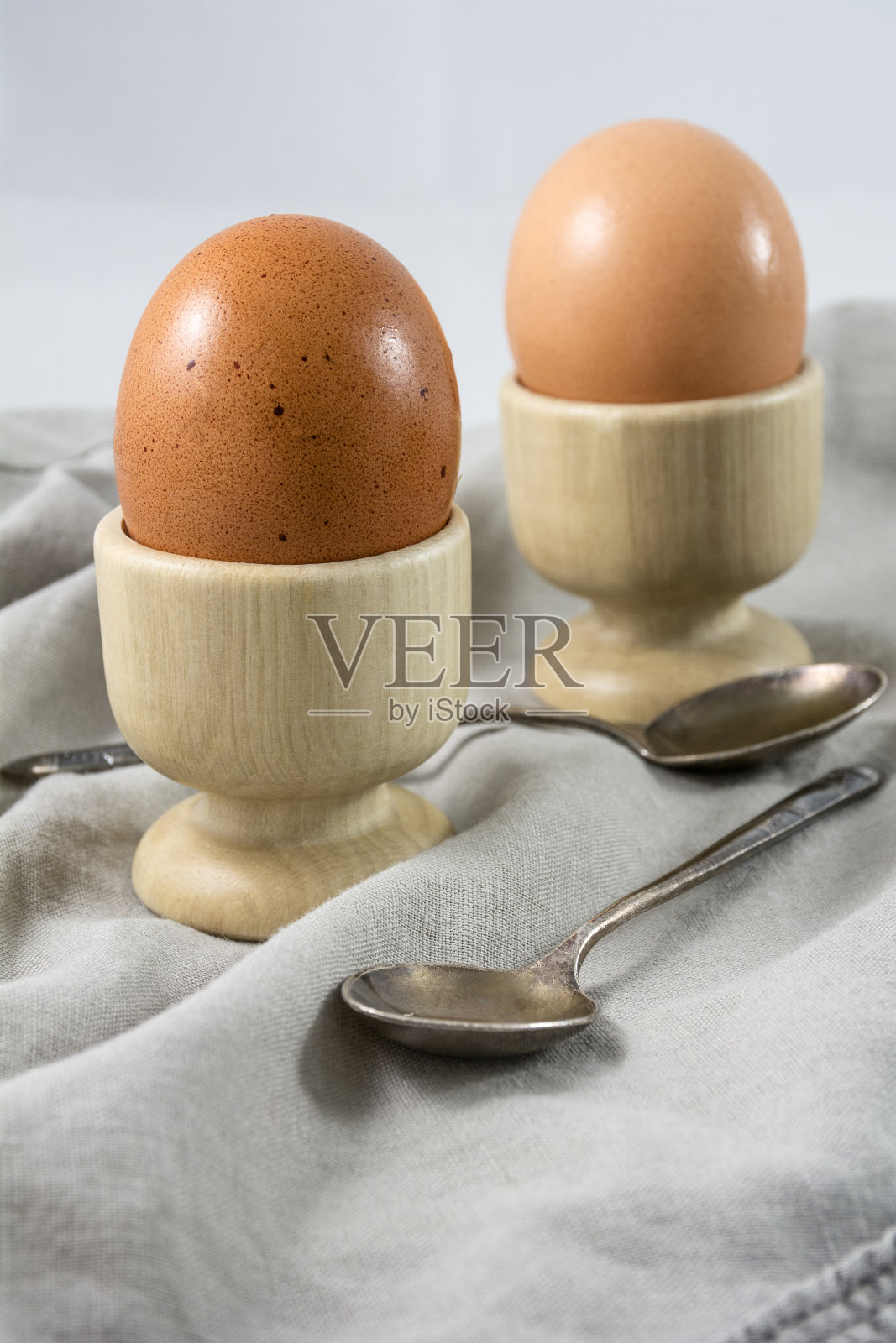 用勺子将煮熟的鸡蛋放入鸡蛋杯中照片摄影图片