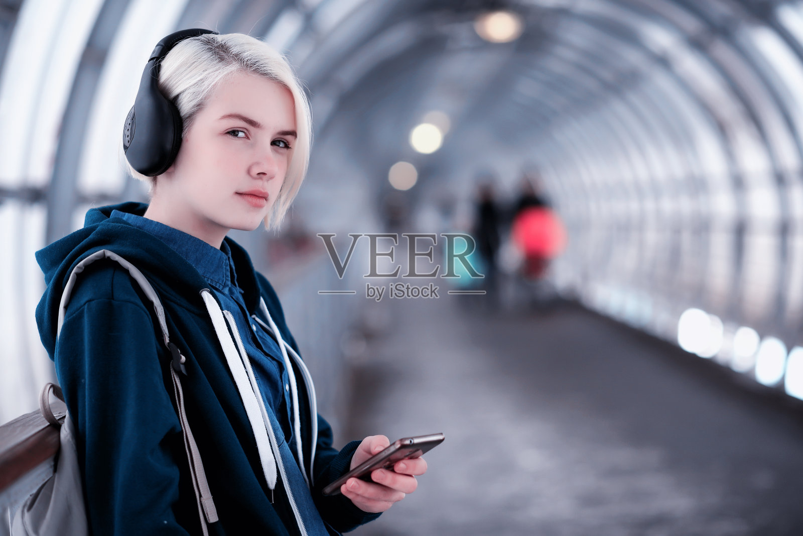 年轻的学生戴着大耳机在地铁里听音乐照片摄影图片
