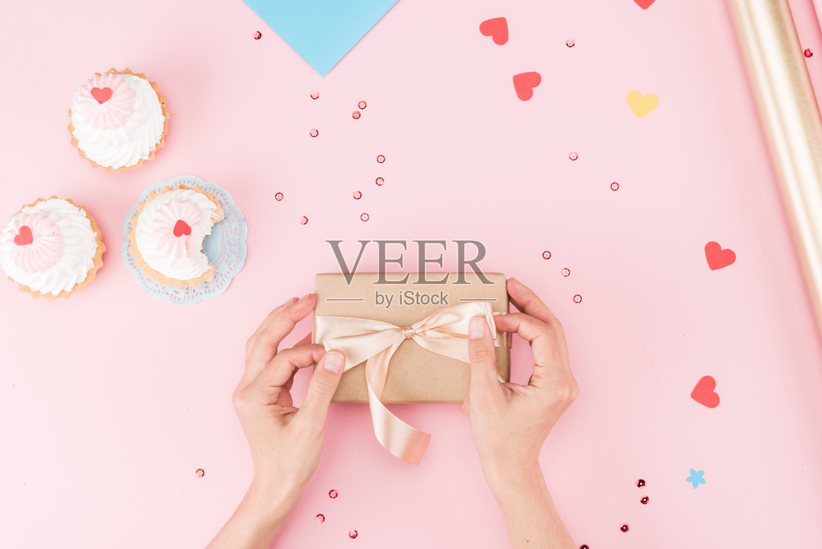 部分俯视图的手包装礼盒和美味的纸杯蛋糕在粉红色，生日派对的概念照片摄影图片