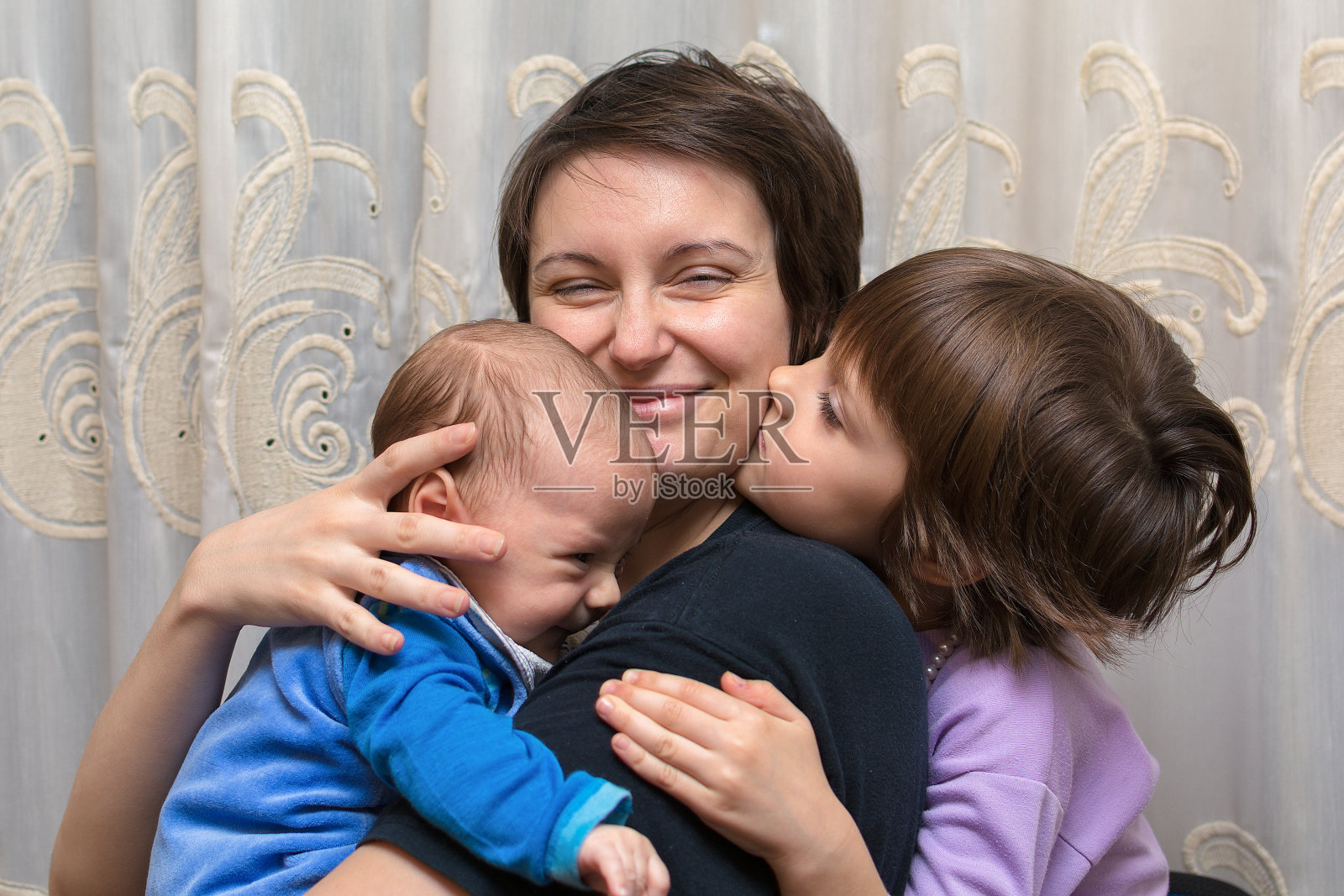 儿子和女儿亲吻她的母亲照片摄影图片