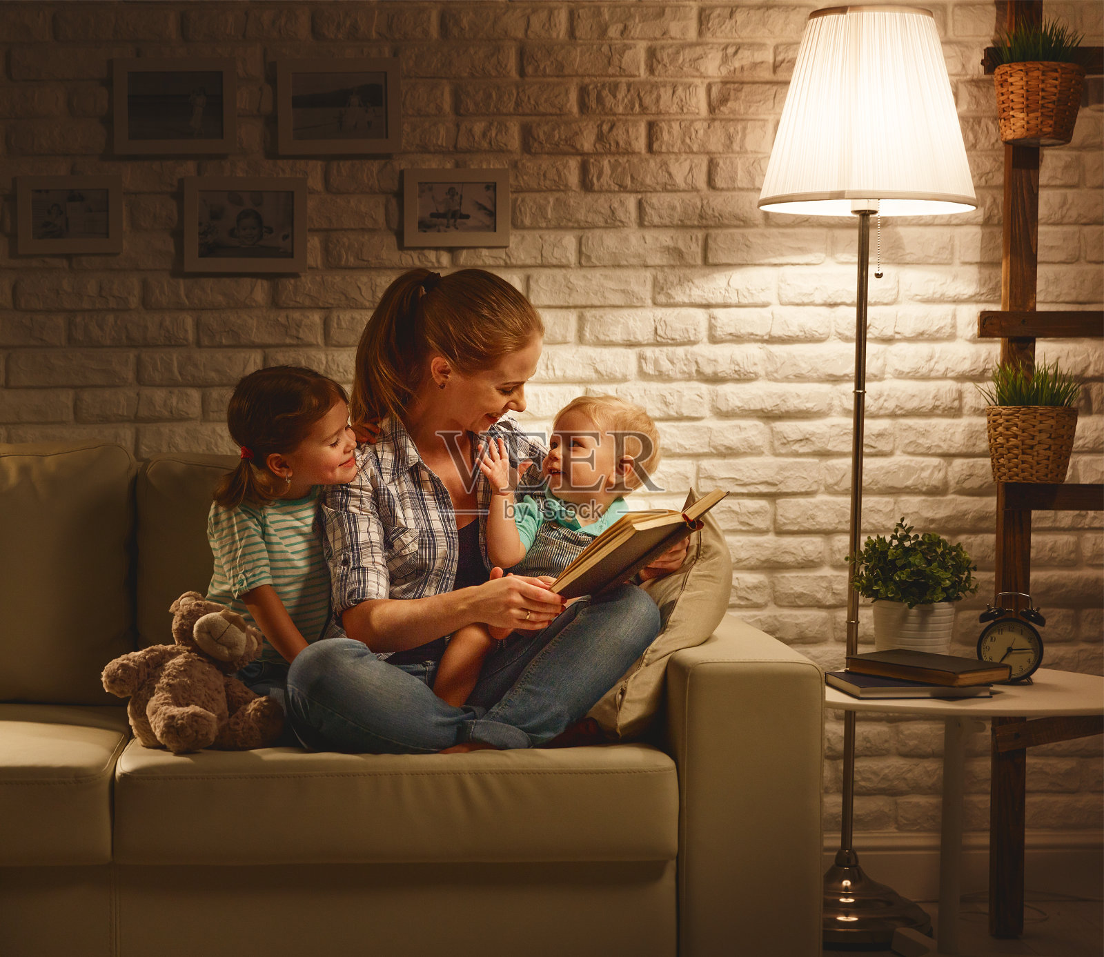 家人睡觉前，妈妈在晚上给孩子们读关于灯的书照片摄影图片