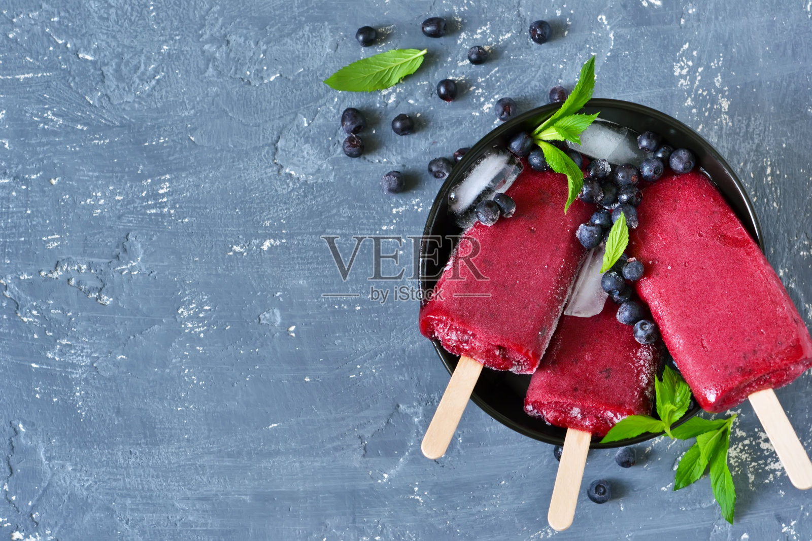 浆果冰淇淋，蓝莓和薄荷在混凝土蓝色背景。夏天冷甜点。照片摄影图片