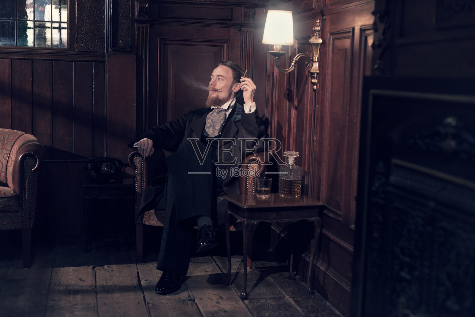1900年复古的留着胡子的时尚男士。坐在旧房间里。照片摄影图片