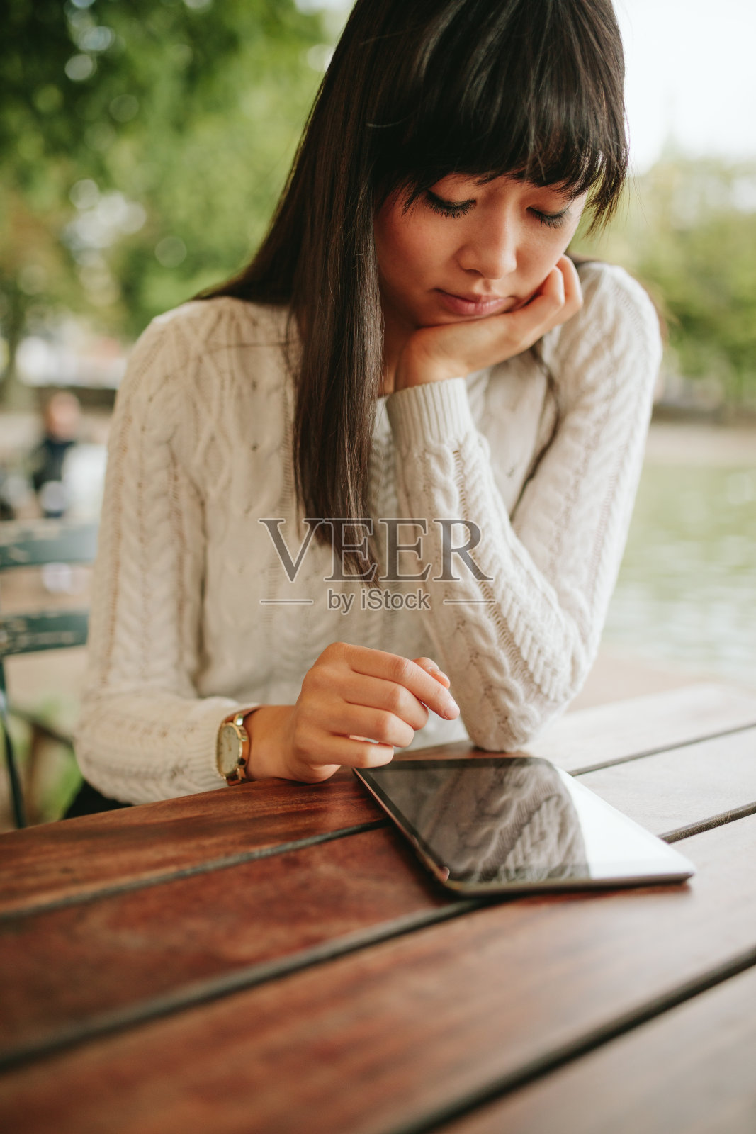 一名年轻女子在户外咖啡馆使用平板电脑。照片摄影图片