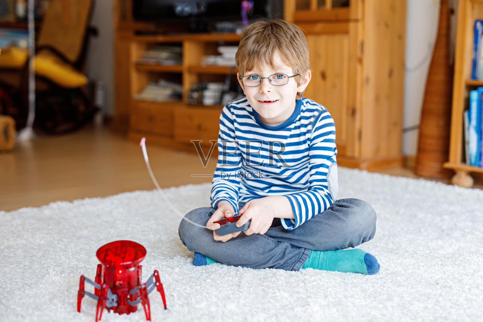 戴眼镜的小男孩在玩机器人蜘蛛玩具。快乐的孩子与探索机器人游戏的乐趣。照片摄影图片