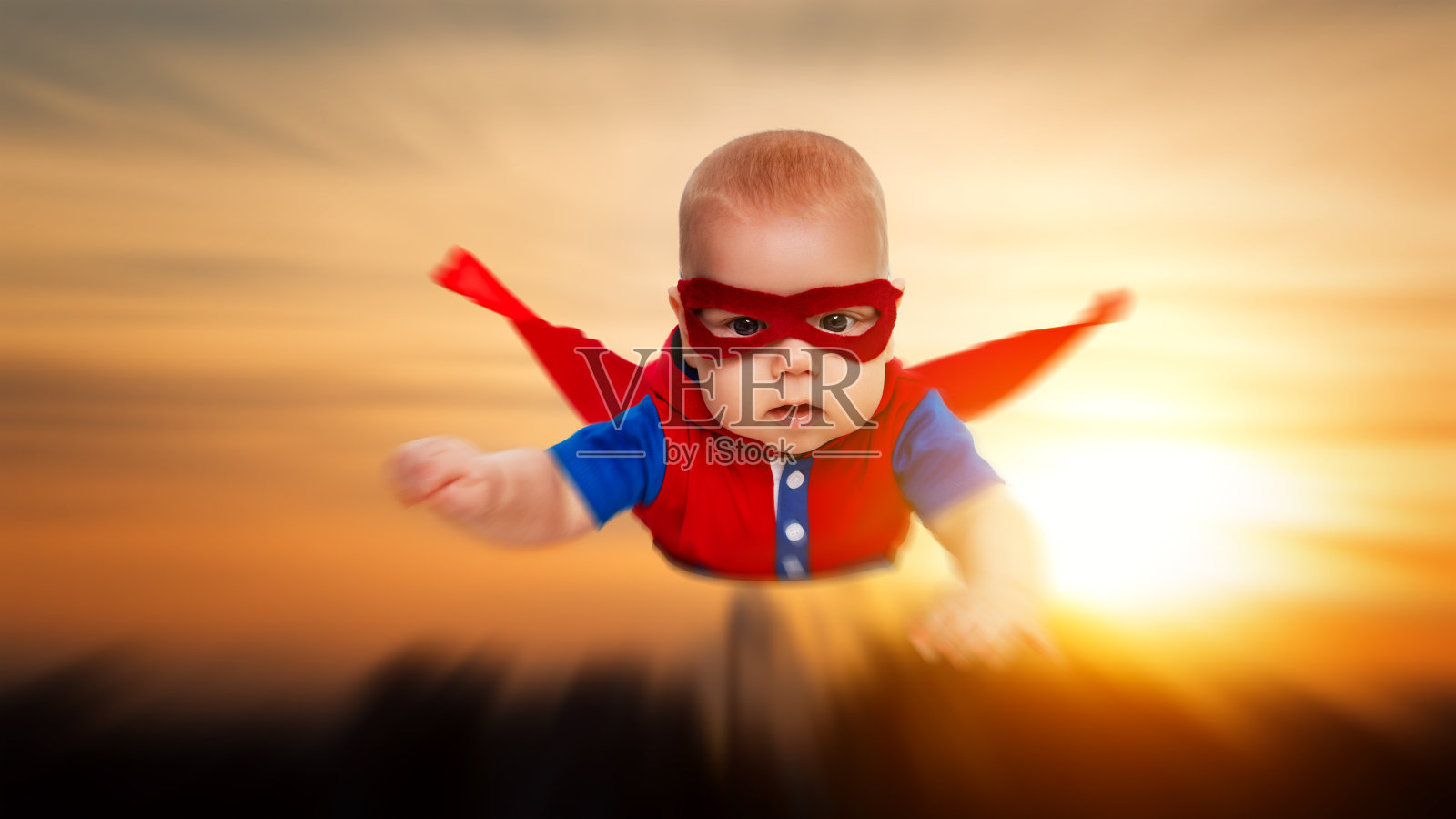 蹒跚学步的小超人，披着红斗篷的超级英雄照片摄影图片