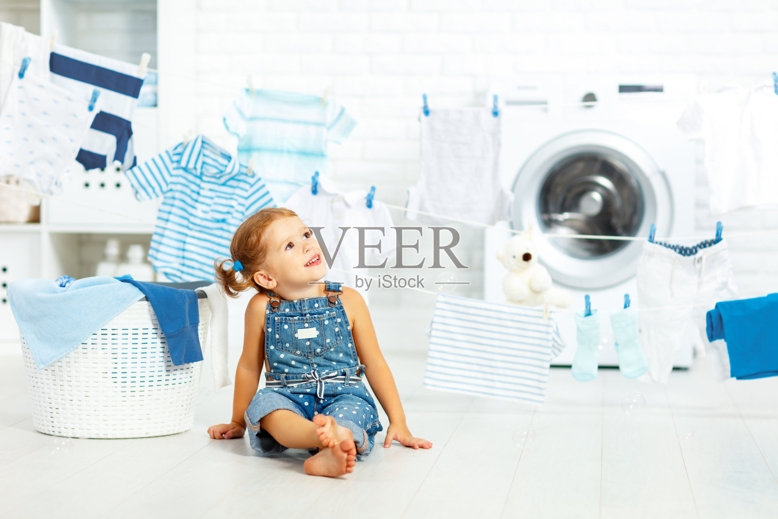 孩子开心快乐的小女孩在洗衣房洗衣服照片摄影图片