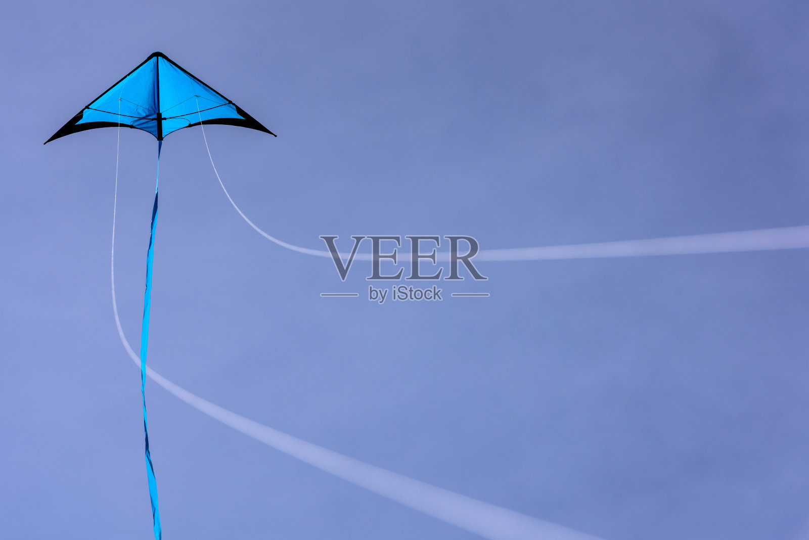 蓝色的风筝漂浮在蓝天上。照片摄影图片