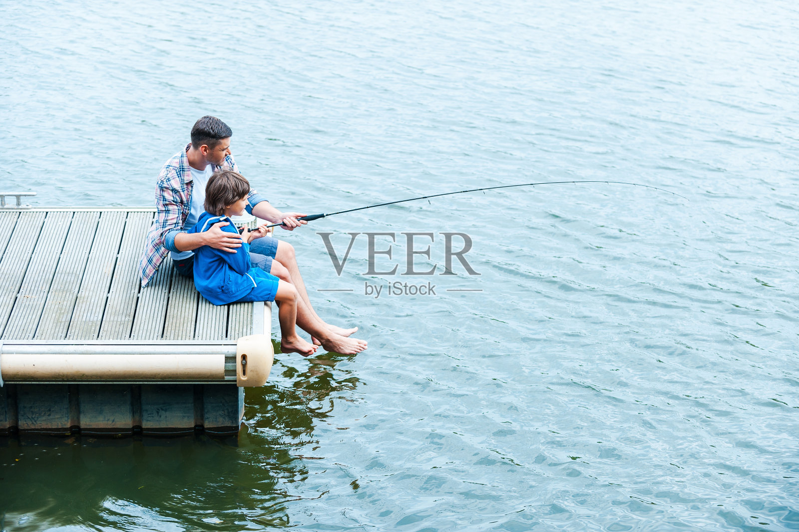 父亲和儿子钓鱼。照片摄影图片