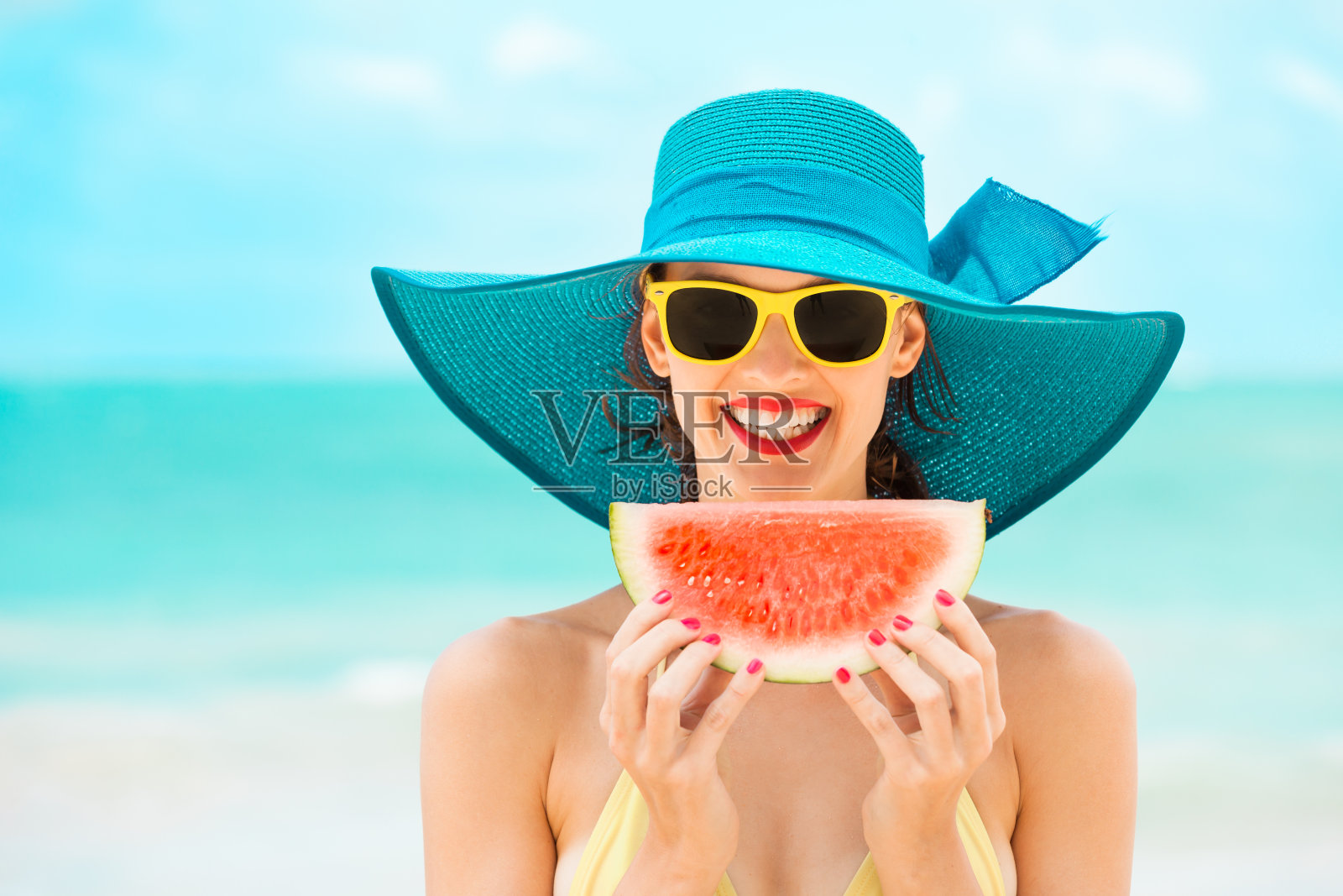 快乐的女人在沙滩上吃着西瓜。照片摄影图片