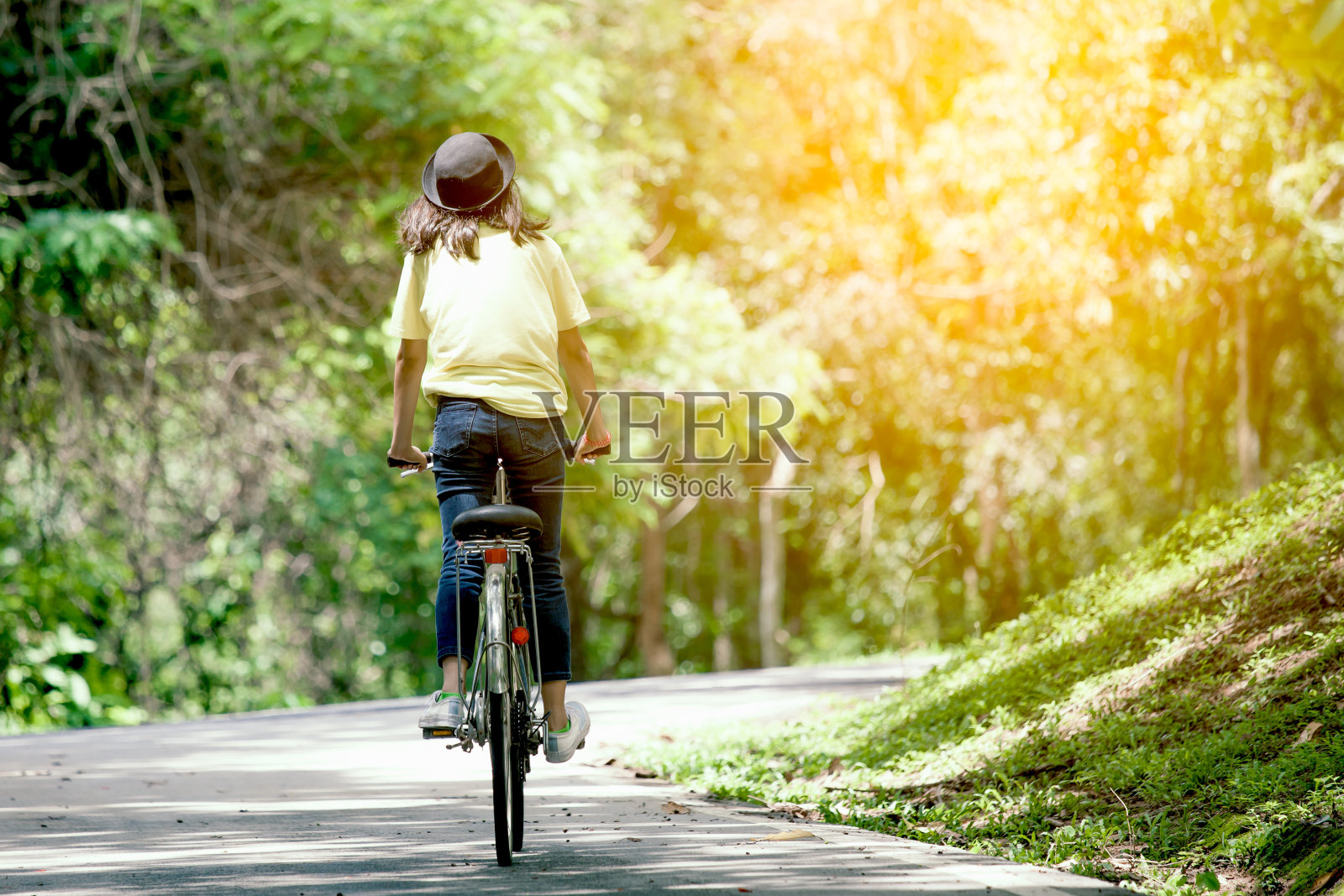 年轻女孩在花园里骑自行车的后视图照片摄影图片