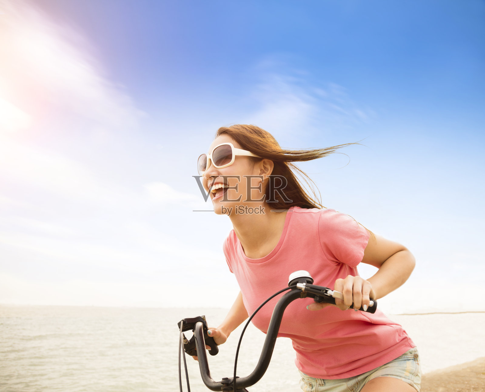 快乐的年轻女子骑着自行车在海滩上照片摄影图片