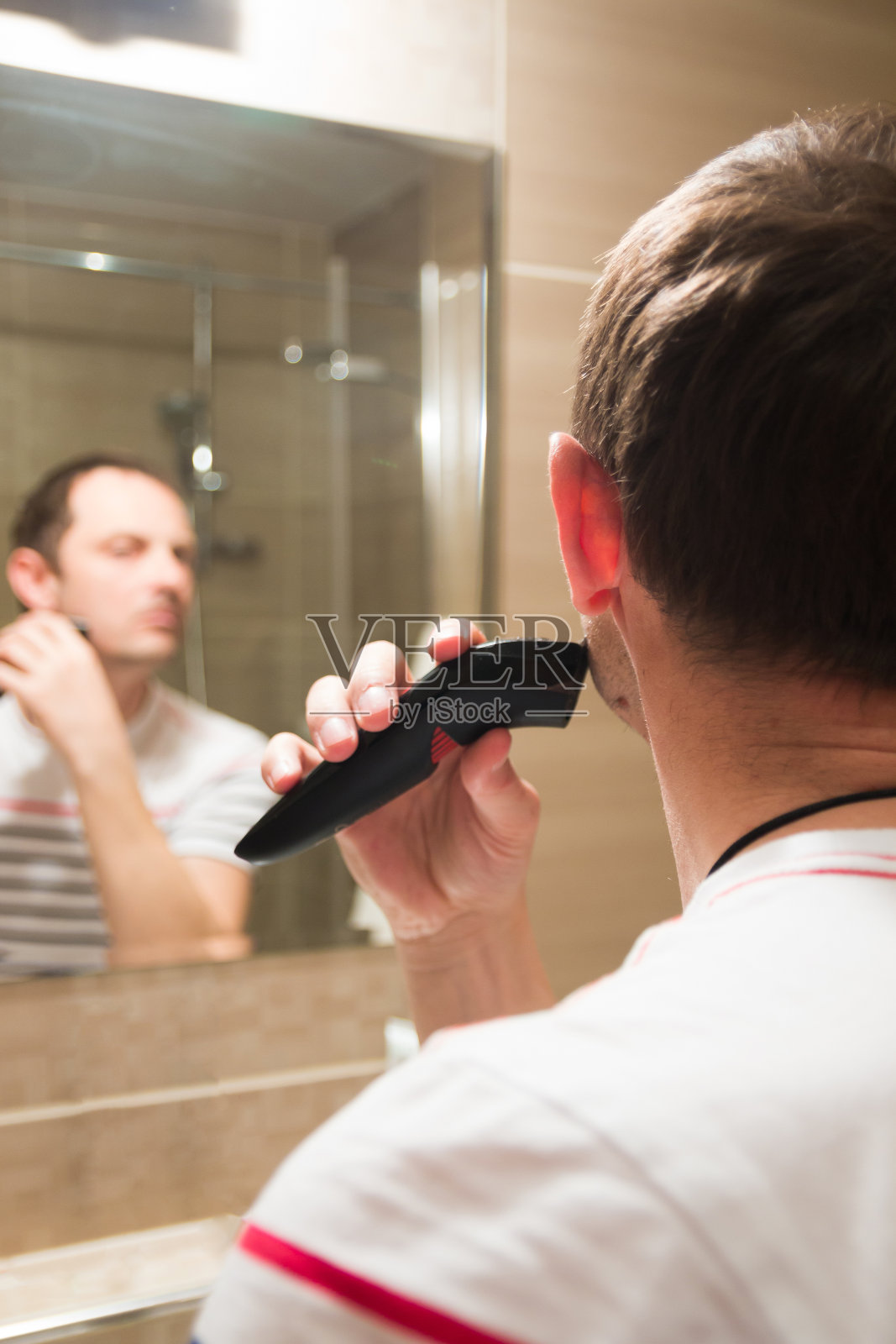 帅哥在浴室里对着镜子刮胡子照片摄影图片