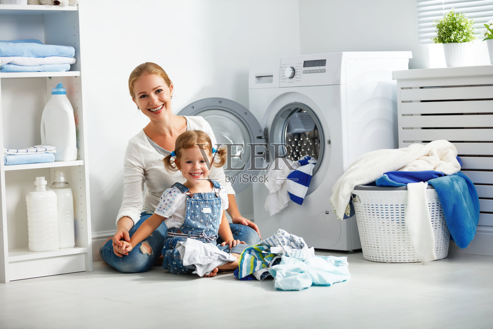 家庭母亲和孩子女孩在洗衣机附近的洗衣房照片摄影图片