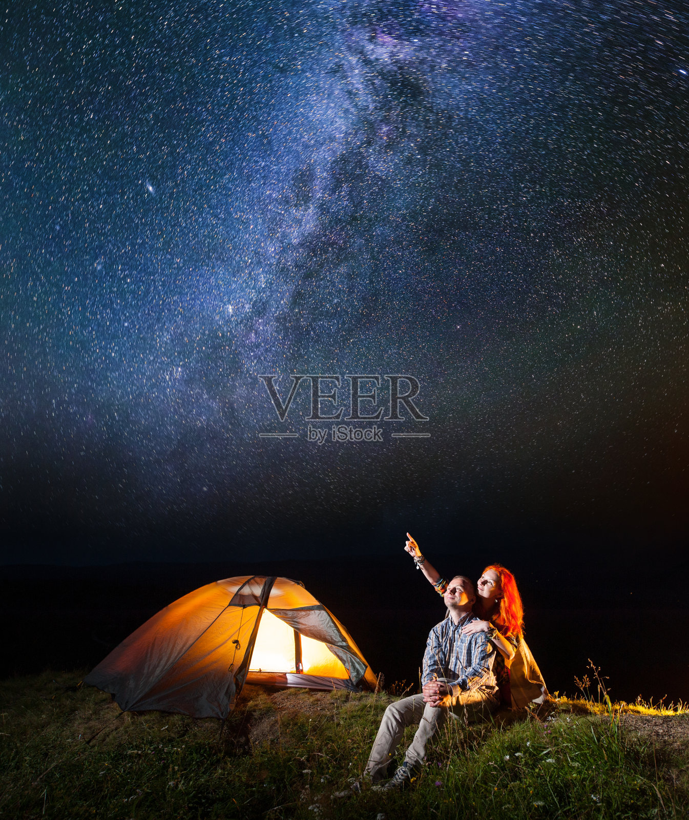 一对游客夫妇，女孩和男孩看着夜空中闪耀的星空。两人坐在露营附近照片摄影图片