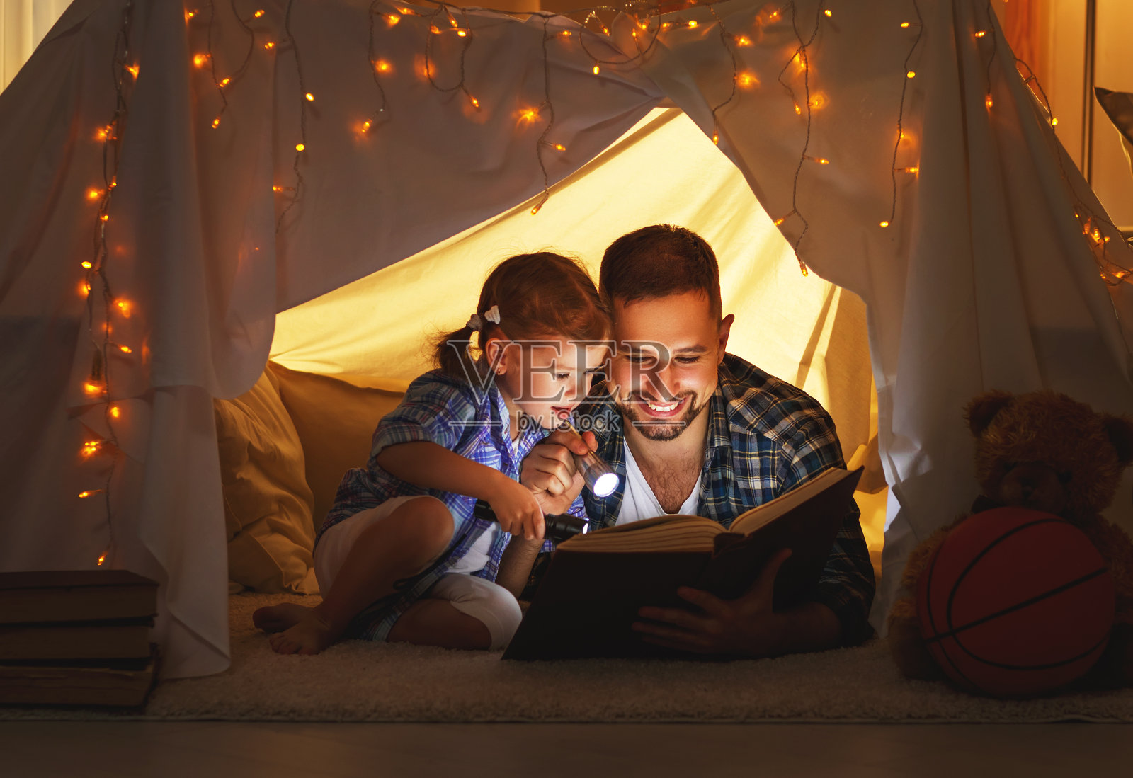 幸福的家庭，爸爸和女儿在家里的帐篷里看书照片摄影图片