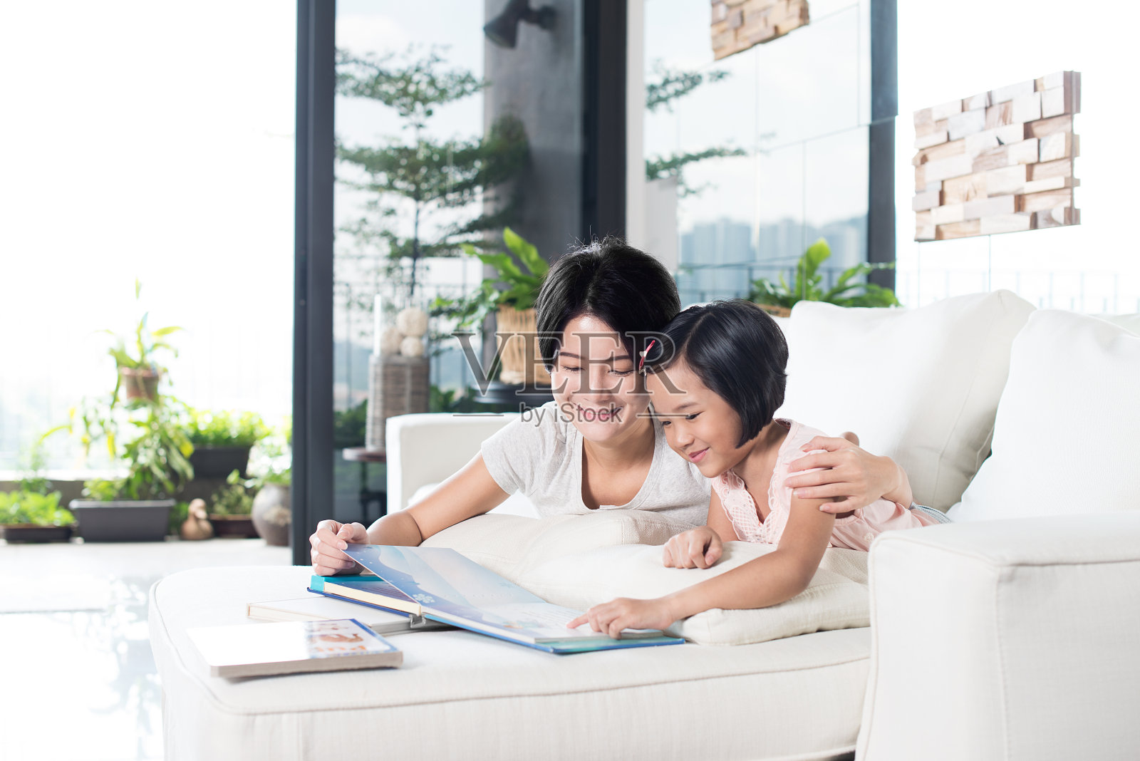 亚洲母亲和女儿在家里看书。照片摄影图片