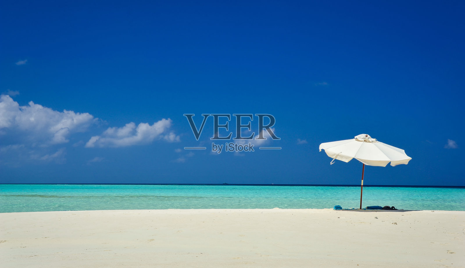 伞在田园诗般的热带沙滩上。白色的沙滩伞和蓝色的天空。海滩上的阳光和雨伞。夏日海滩景观。照片摄影图片