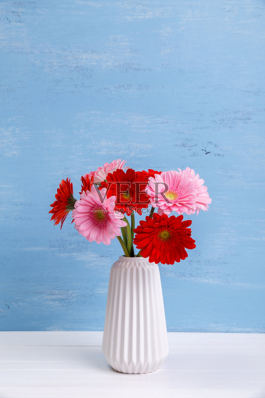 木制背景上的花瓶中的非洲菊。照片摄影图片