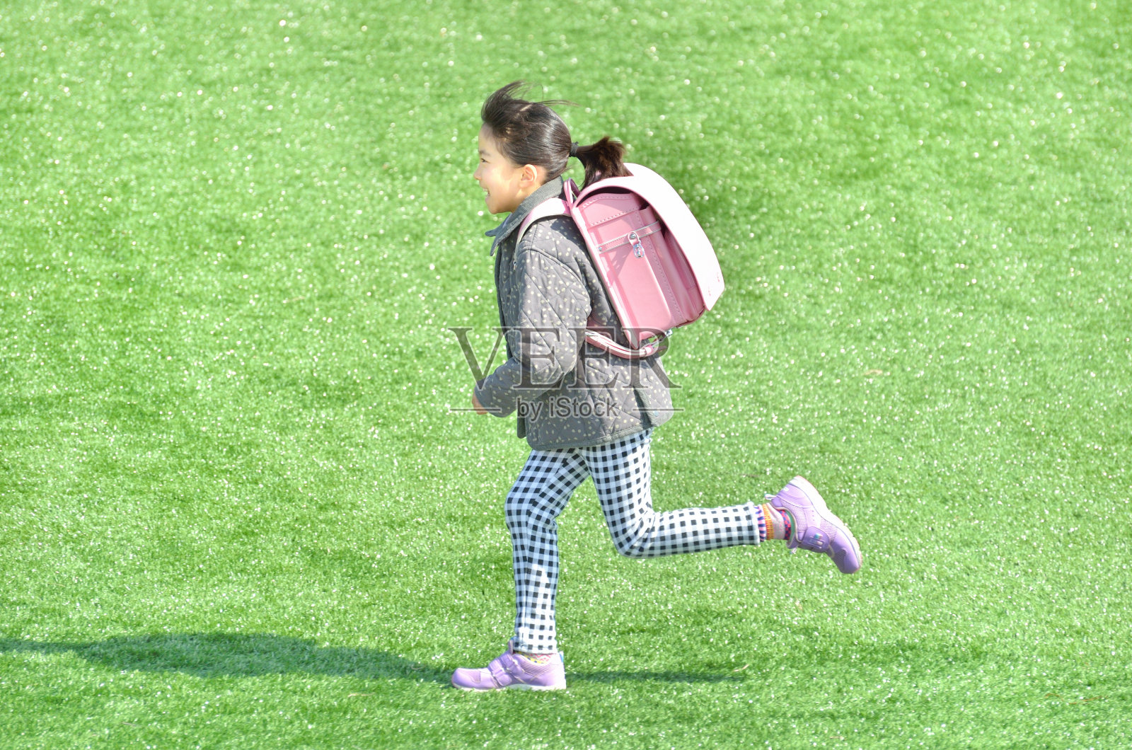 芝生広場で走る女の子（ランドセル、冬）照片摄影图片