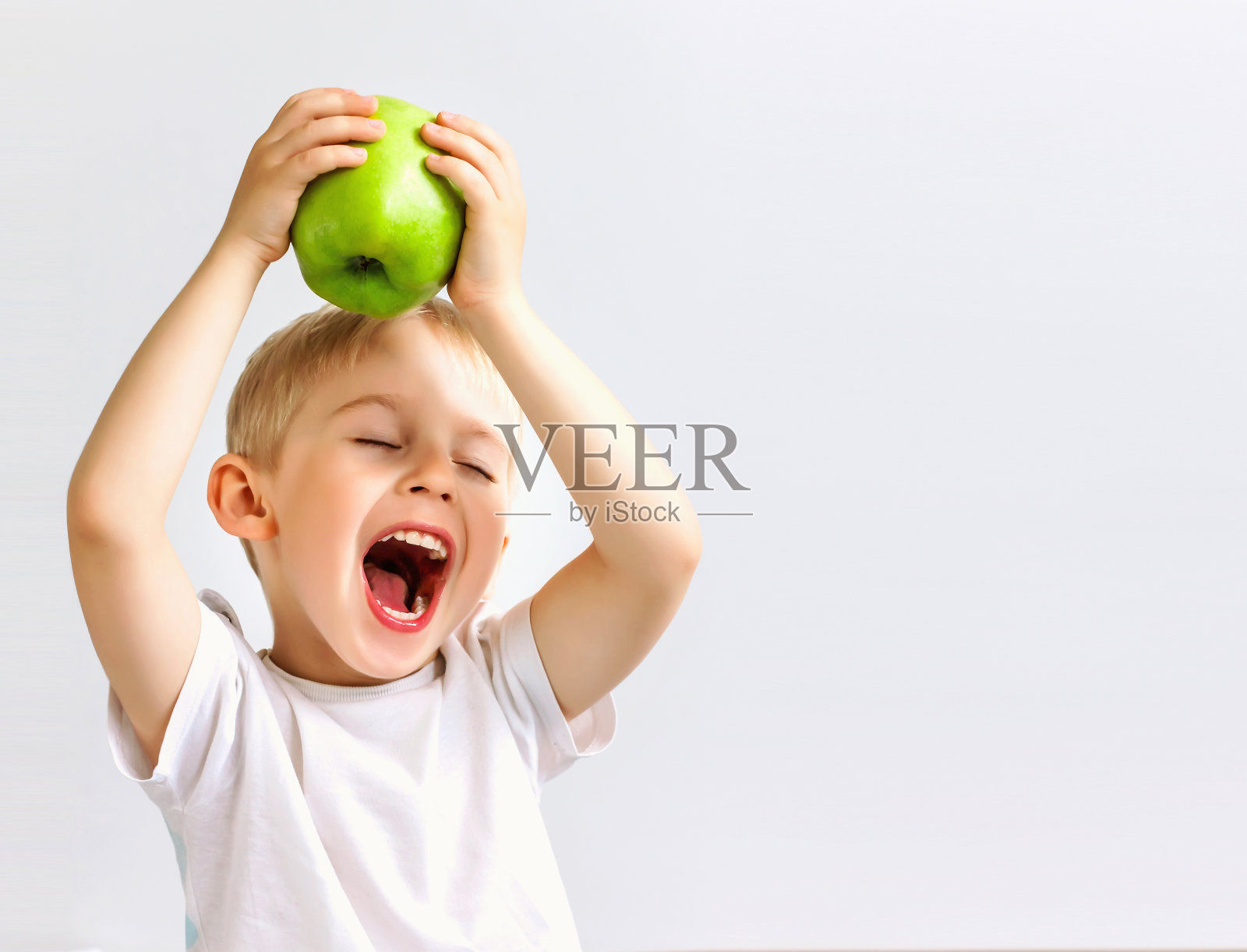 小男孩拿着一个绿色的大苹果，照片摄影图片
