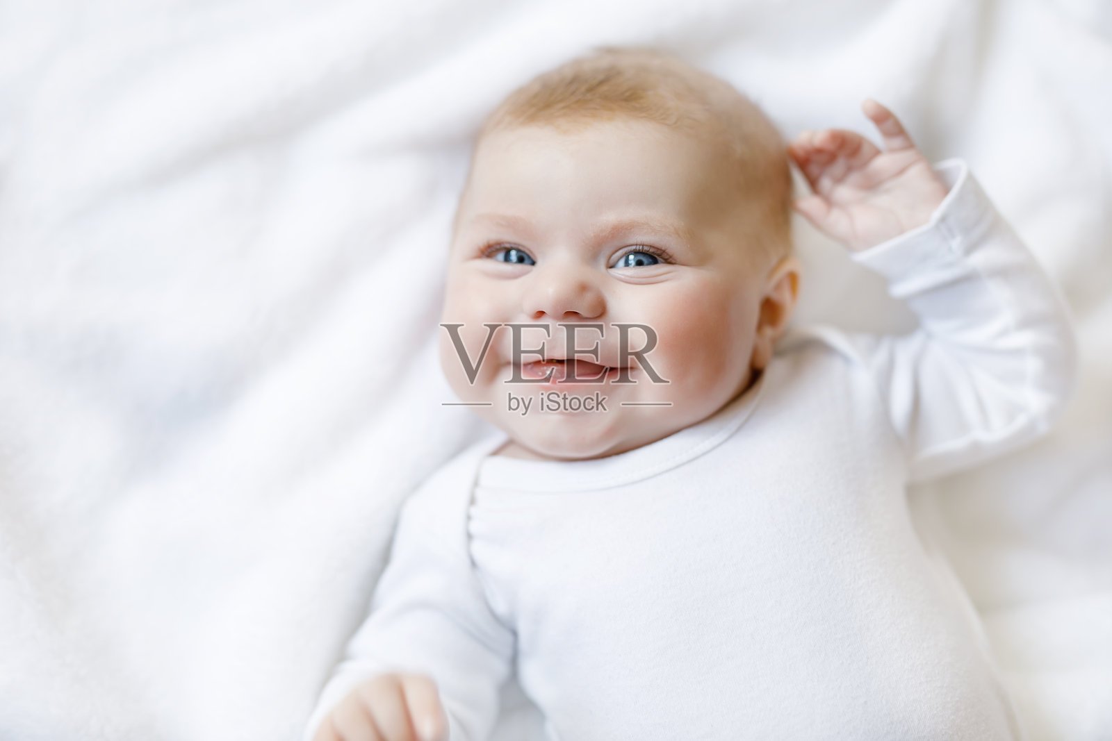 女婴穿着白色的毛巾或冬季工作服在白色的阳光卧室里照片摄影图片