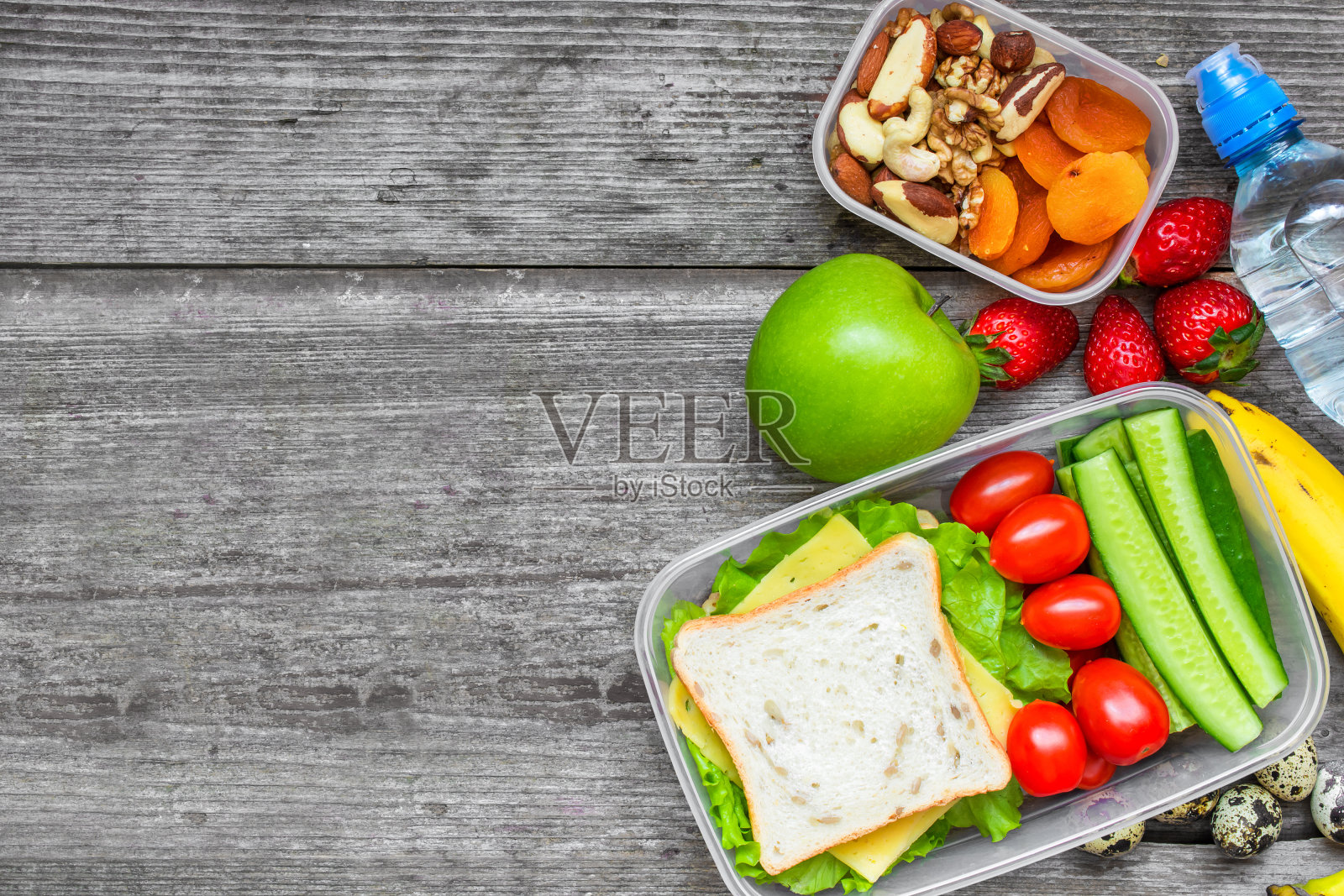 健康午餐盒，有三明治，鸡蛋和新鲜蔬菜，一瓶水，坚果和水果照片摄影图片