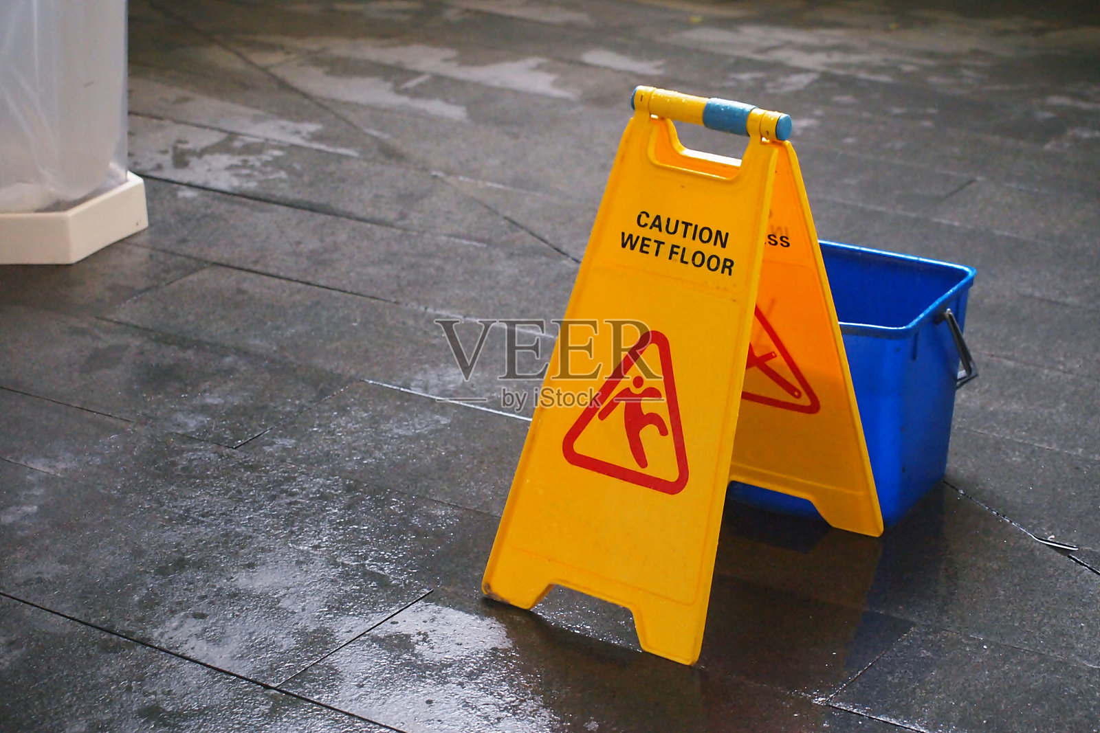 黄色警告湿地板标志与蓝色桶照片摄影图片