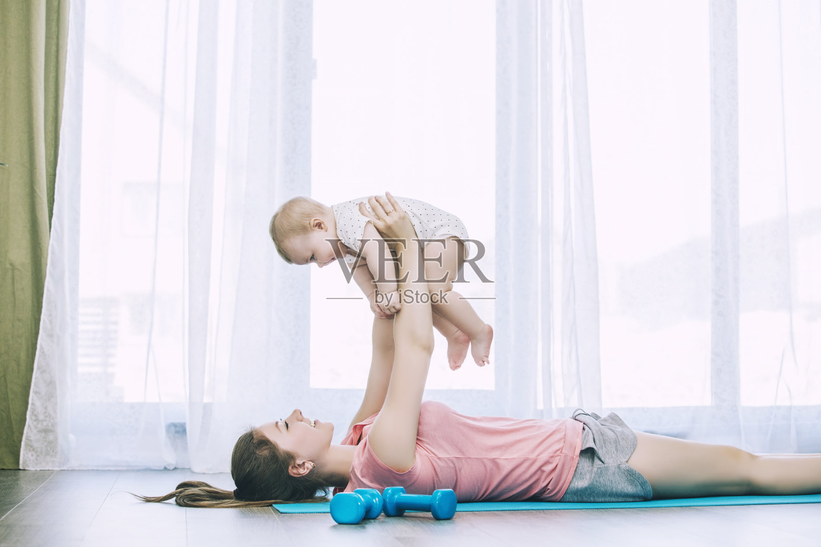 母亲和幼童做健身在一个运动垫在家里一起和微笑照片摄影图片