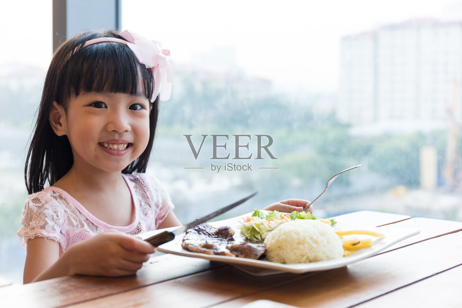 微笑的亚洲中国小女孩吃羊肉排配米饭照片摄影图片