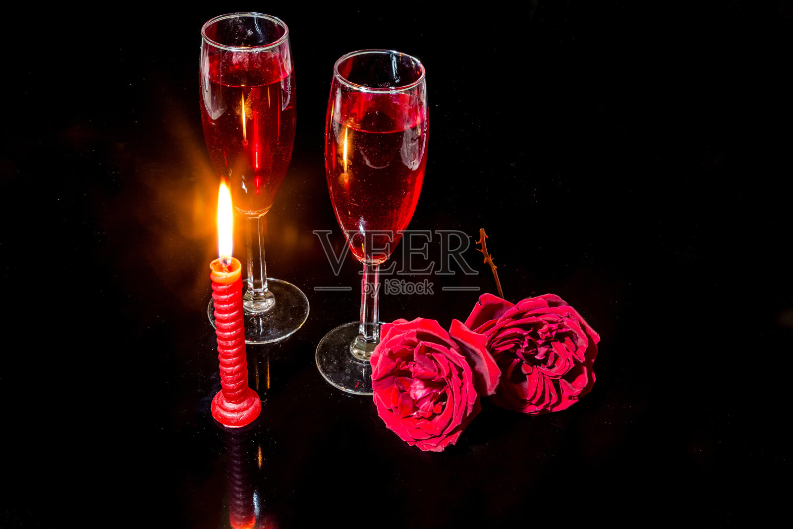 烛光、红玫瑰、红酒杯，映衬着黑暗的背景，营造出浪漫的氛围。照片摄影图片