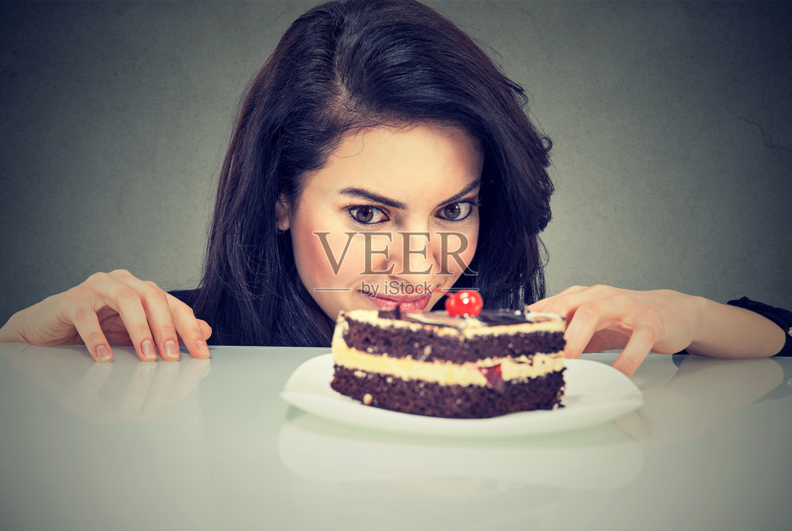女人渴望蛋糕甜点，渴望吃，孤立在灰色的背景照片摄影图片