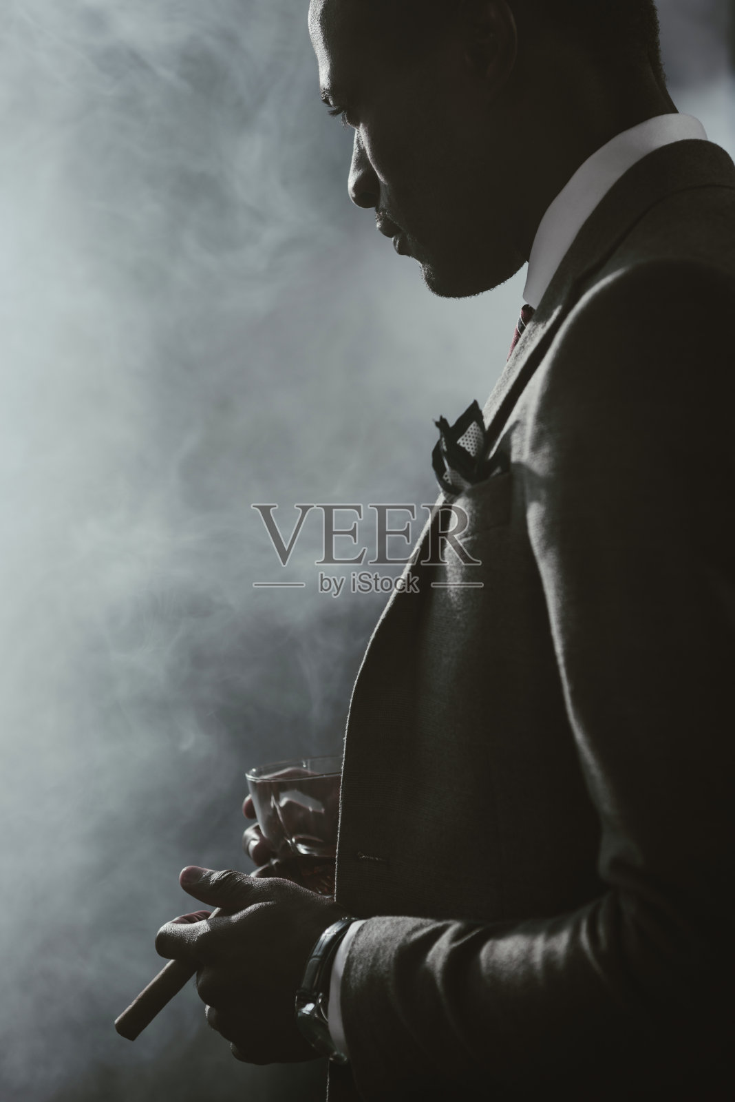 自信的非裔美国商人穿着西装，喝着威士忌抽着雪茄照片摄影图片