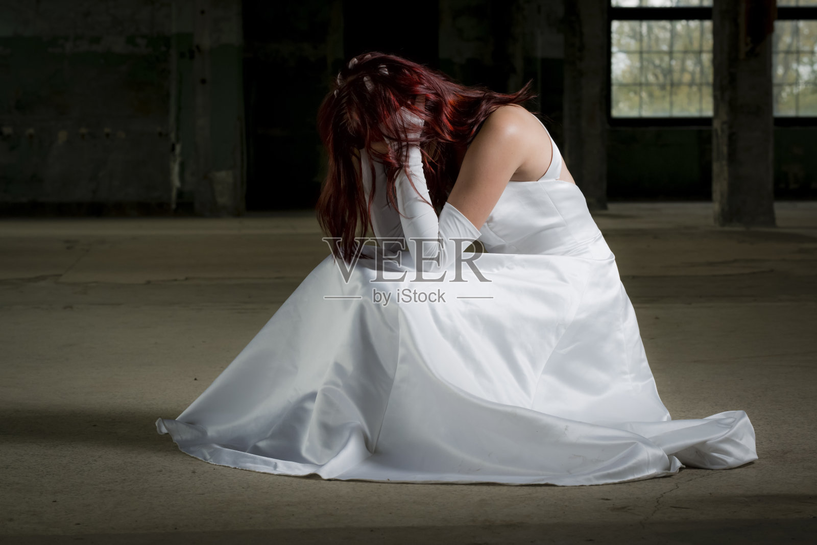 年轻的新娘坐在一幢老房子里，对她的决定感到后悔照片摄影图片