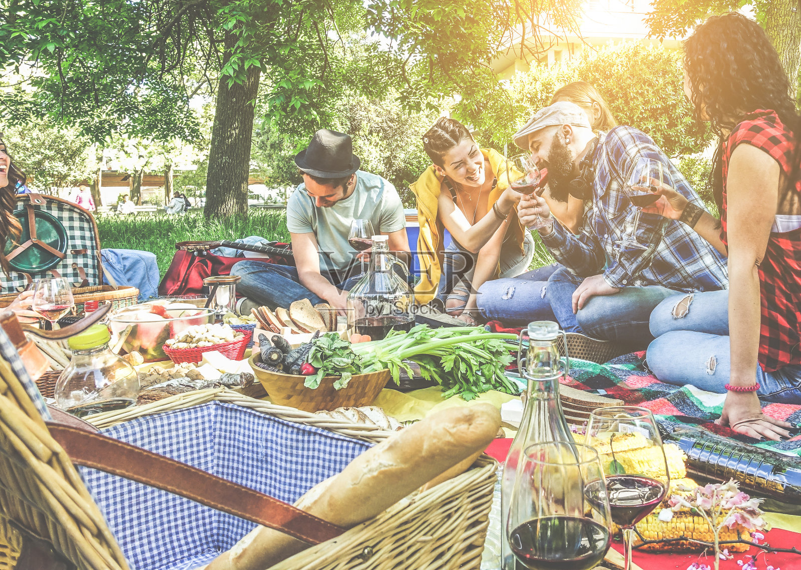 一群朋友在户外野餐与红酒欢呼-年轻时尚的人们在夏天的午餐时间吃和喝的乐趣-关注底杯-青年概念-温暖的对比滤镜照片摄影图片