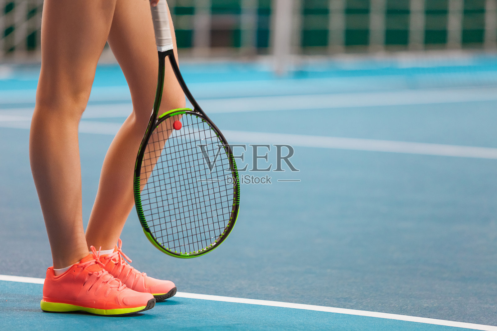 年轻女孩的腿在一个封闭的网球场和球拍照片摄影图片
