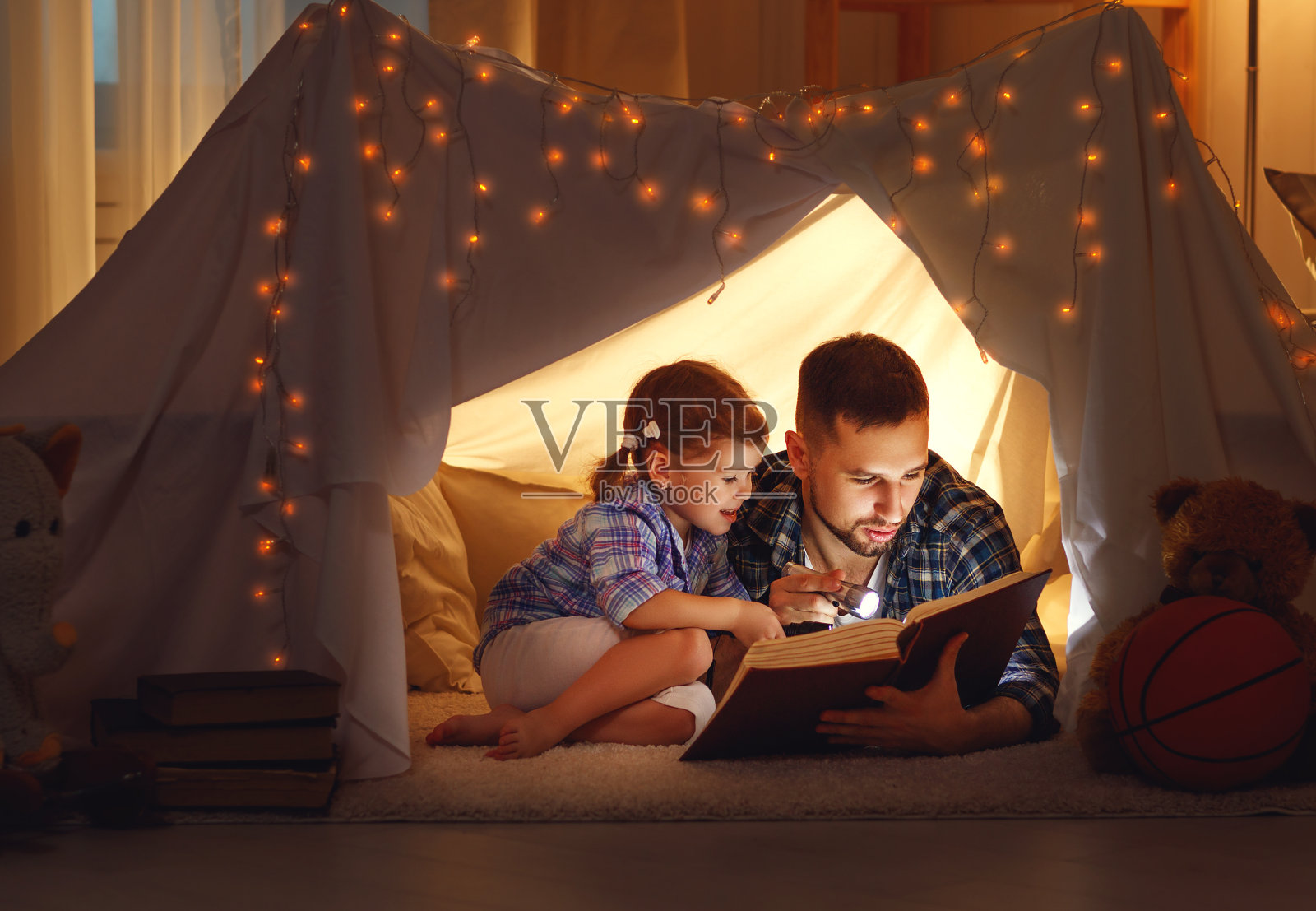 幸福的家庭，爸爸和女儿在家里的帐篷里看书照片摄影图片