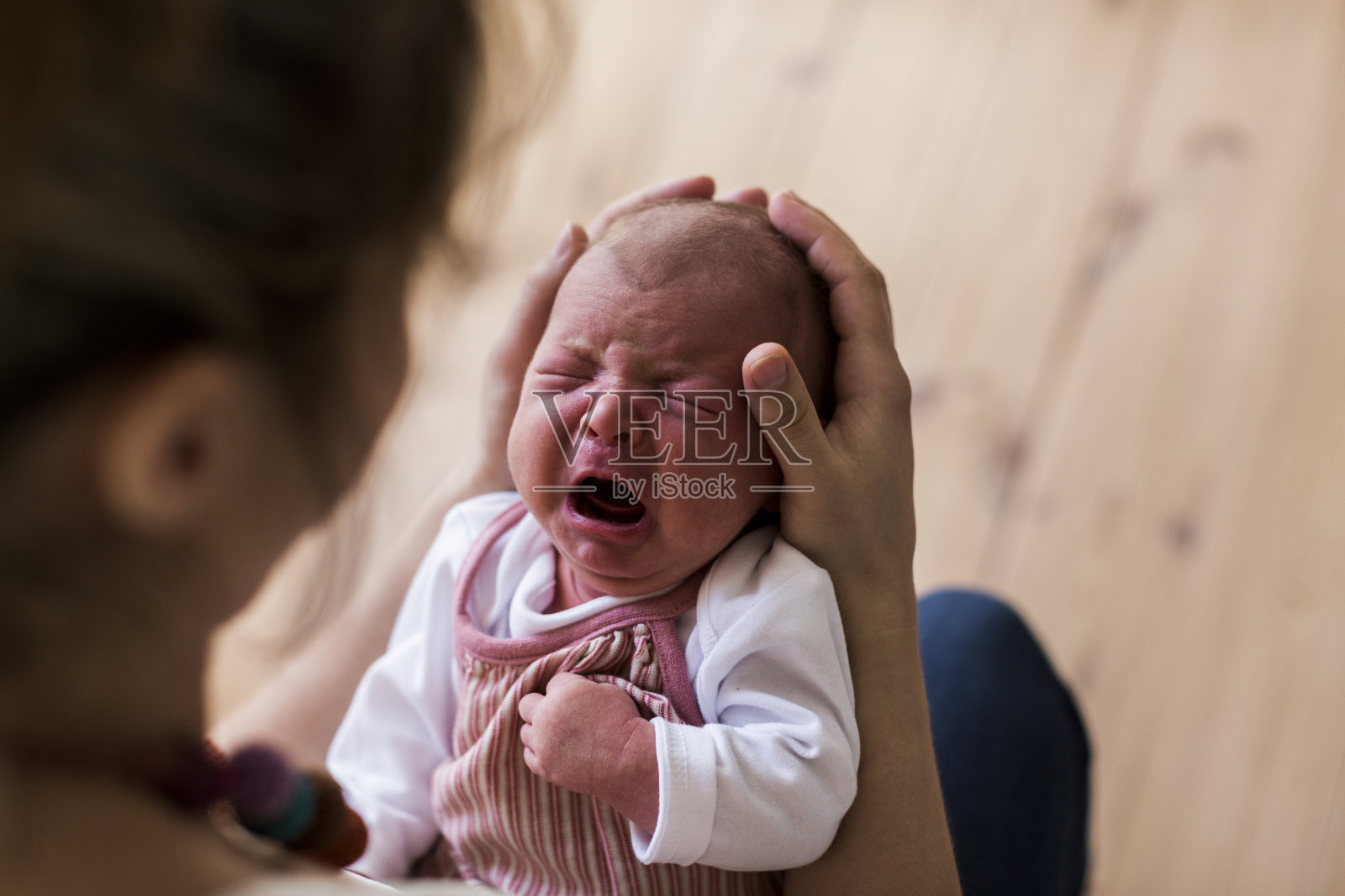 陌生的母亲抱着啼哭的新生女婴。照片摄影图片