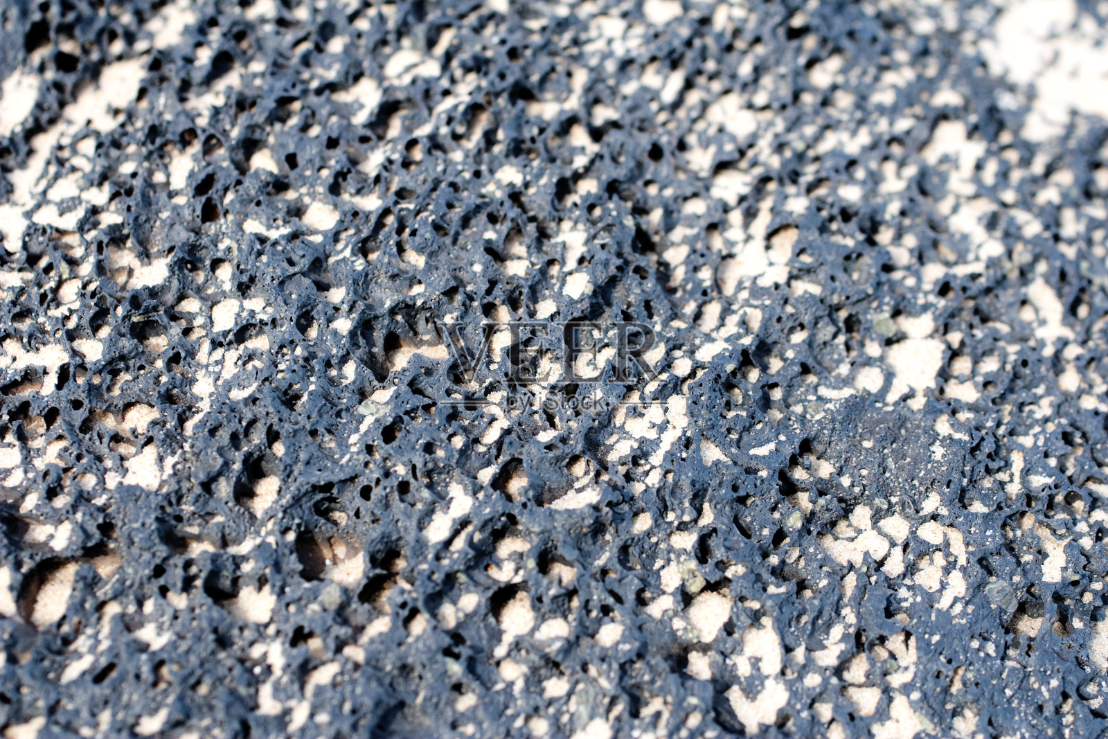 一块黑色的火山浮石，上面有沙子照片摄影图片