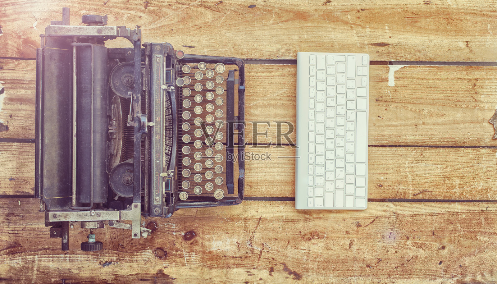 老式的打字机和一个新的键盘在老式的木头背景上照片摄影图片