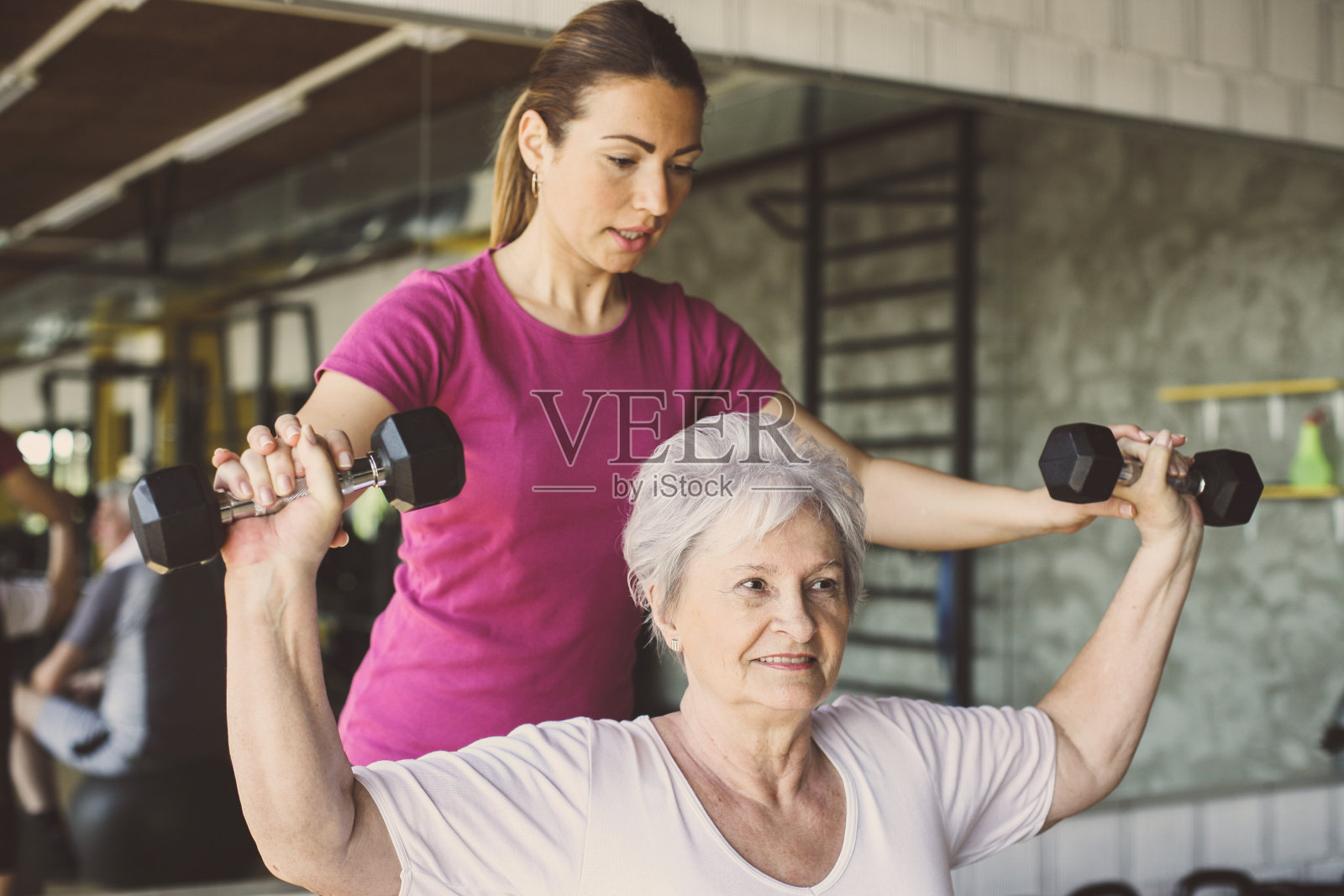 老年妇女在康复中心锻炼。帮助年长女性的私人教练。照片摄影图片