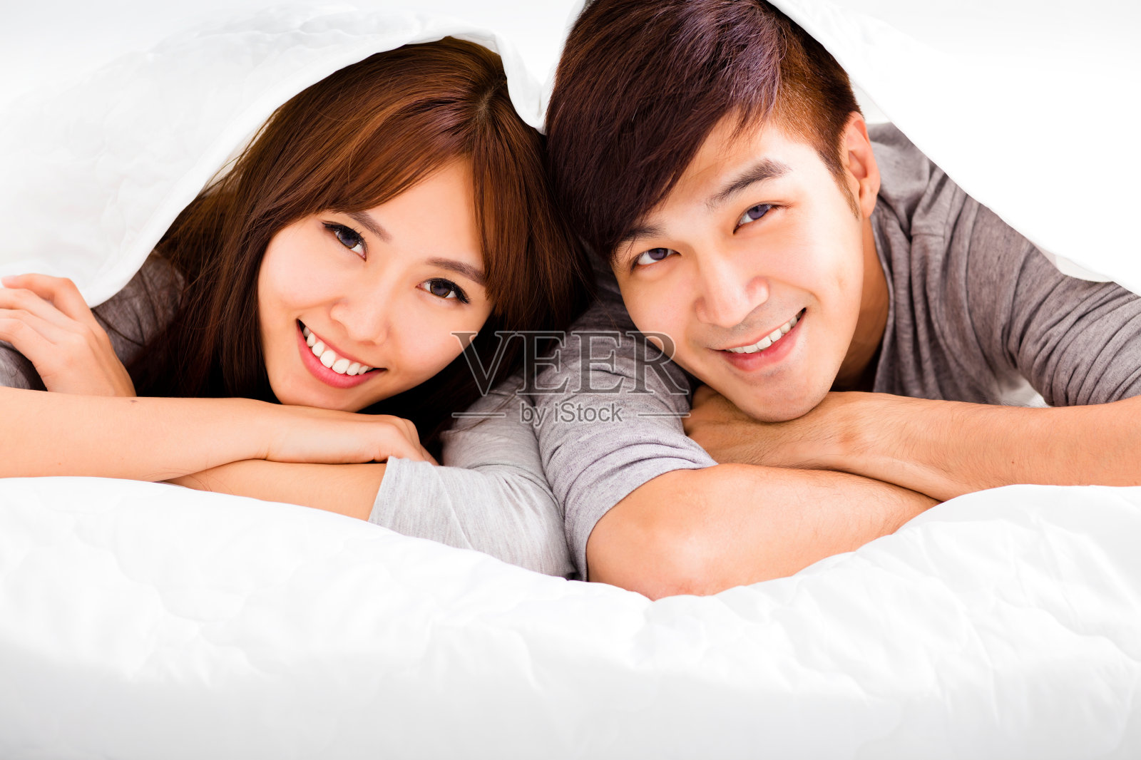 一对幸福的年轻夫妇躺在床上照片摄影图片