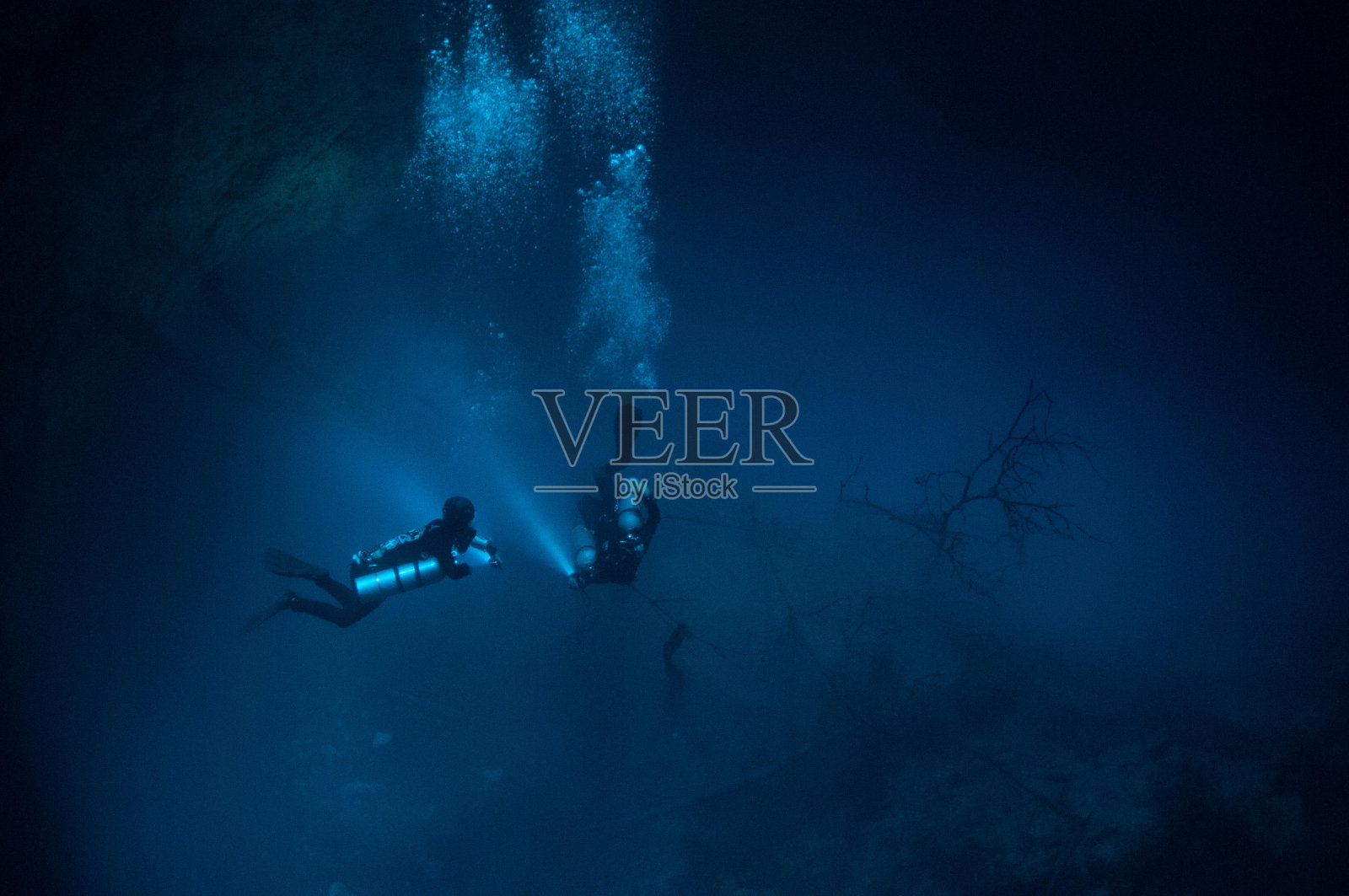 两名潜水员在坑的底部用手电筒和气泡照片摄影图片