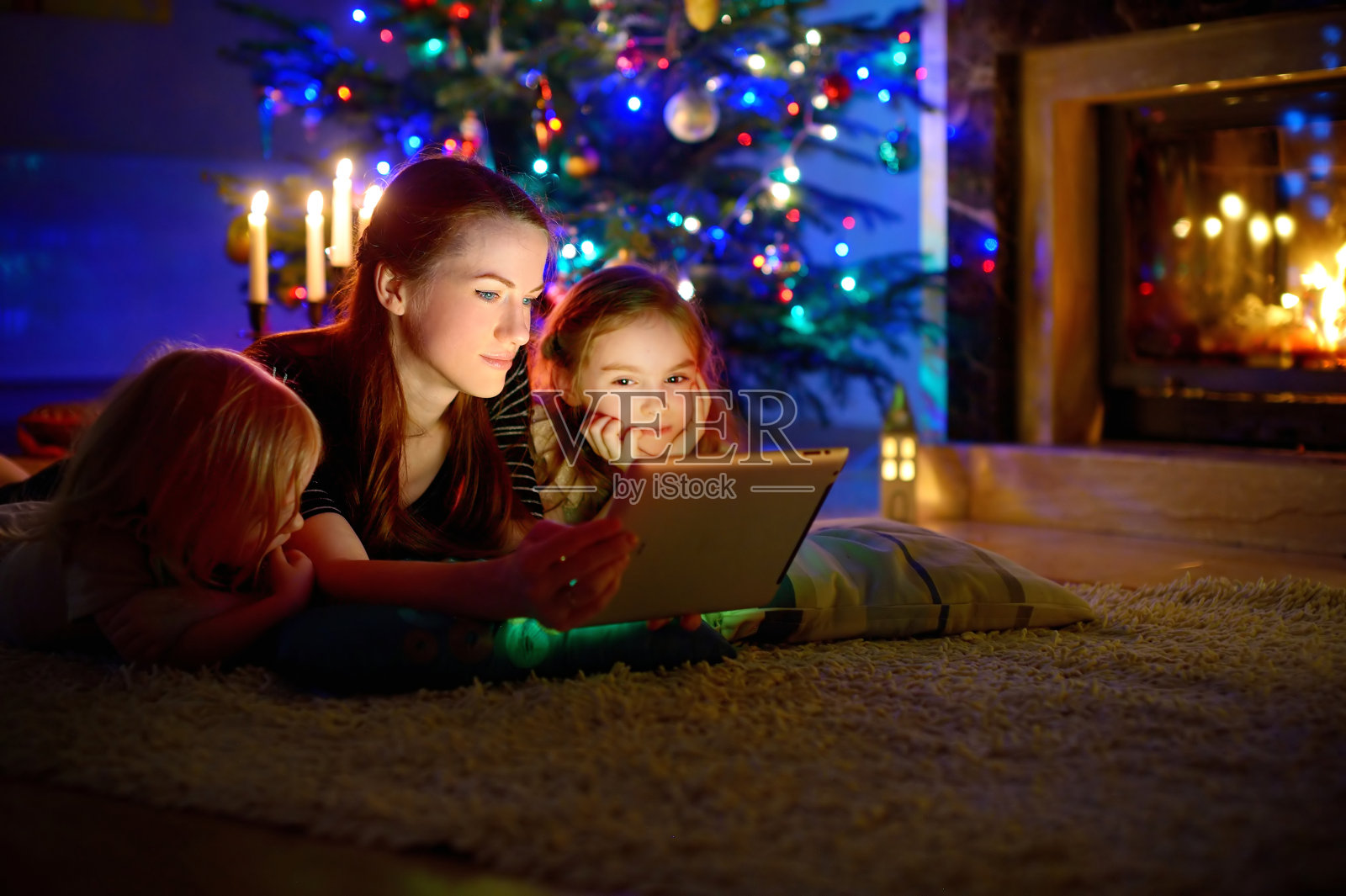 母亲和女儿在圣诞节壁炉旁使用平板电脑照片摄影图片
