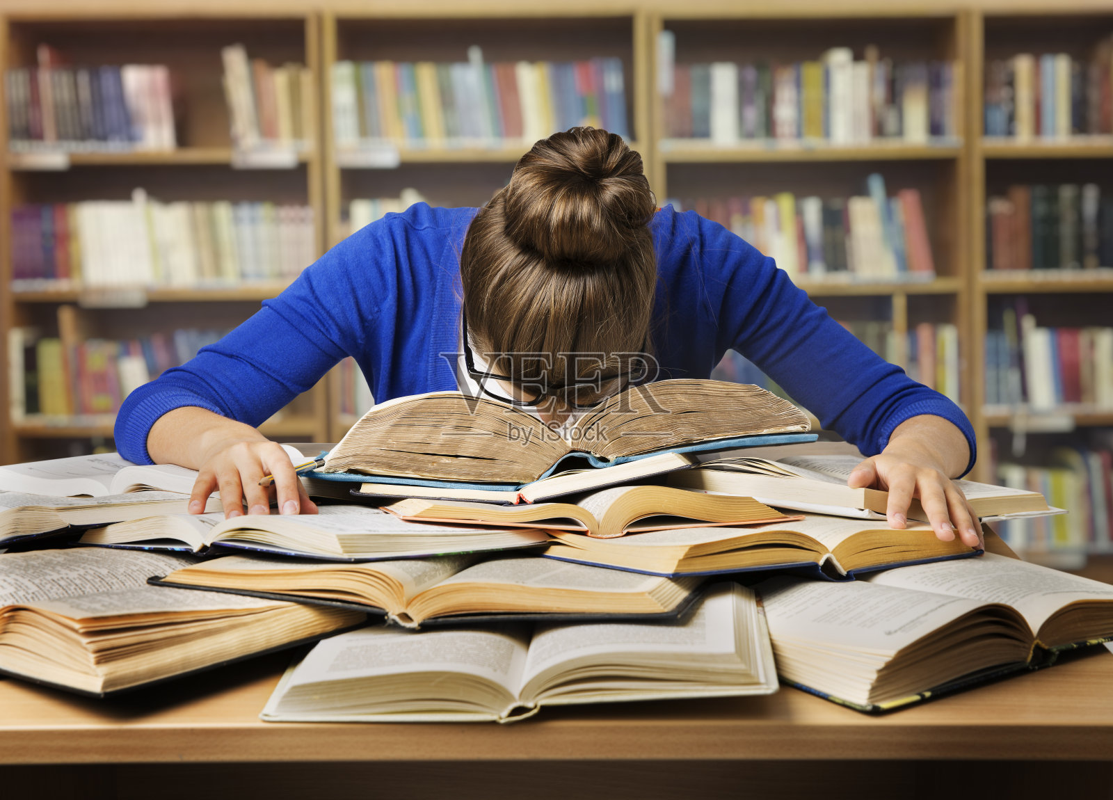 学习的学生睡在书上，疲惫的女孩看书，图书馆照片摄影图片