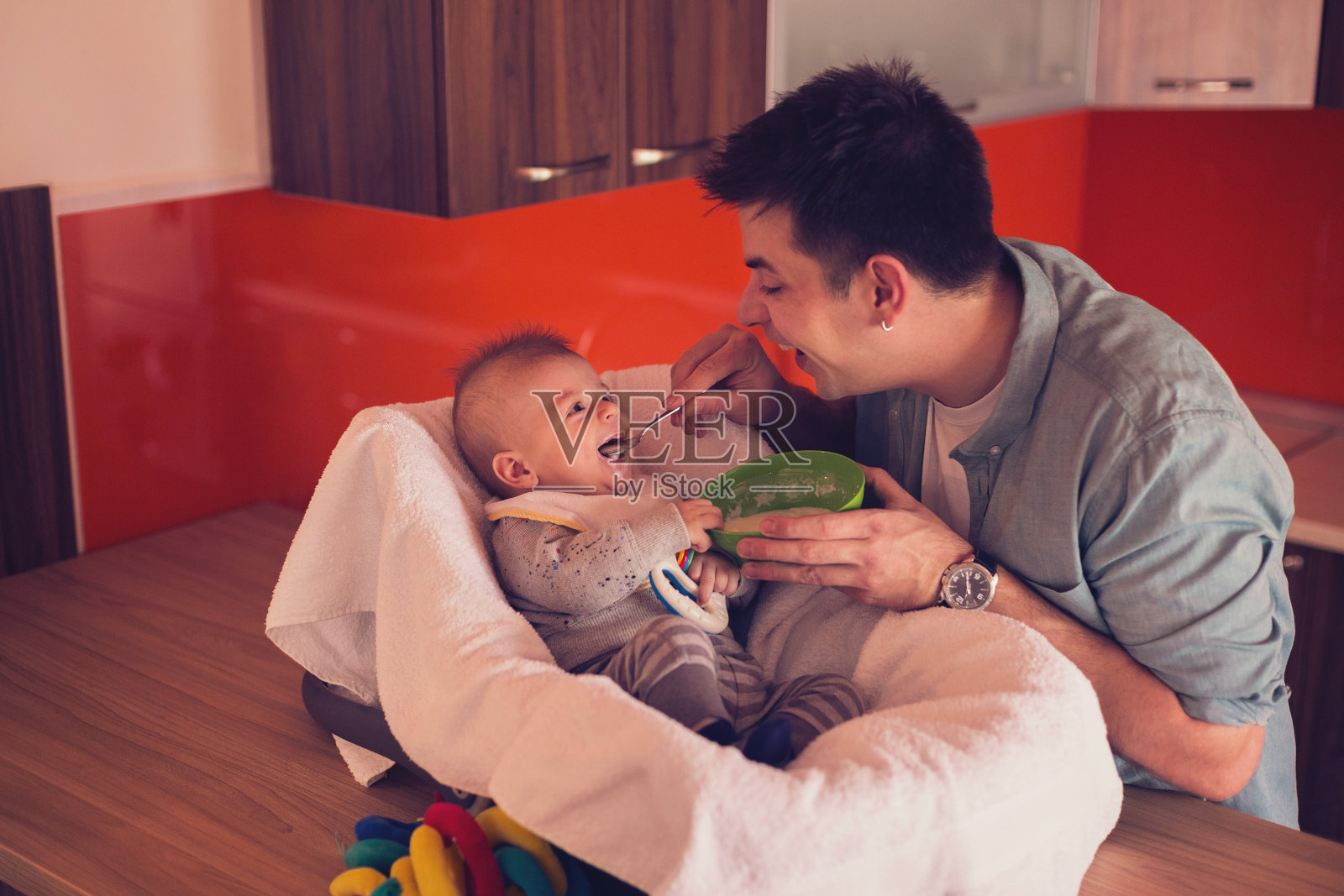 年轻的单身父亲用粥喂小男孩照片摄影图片
