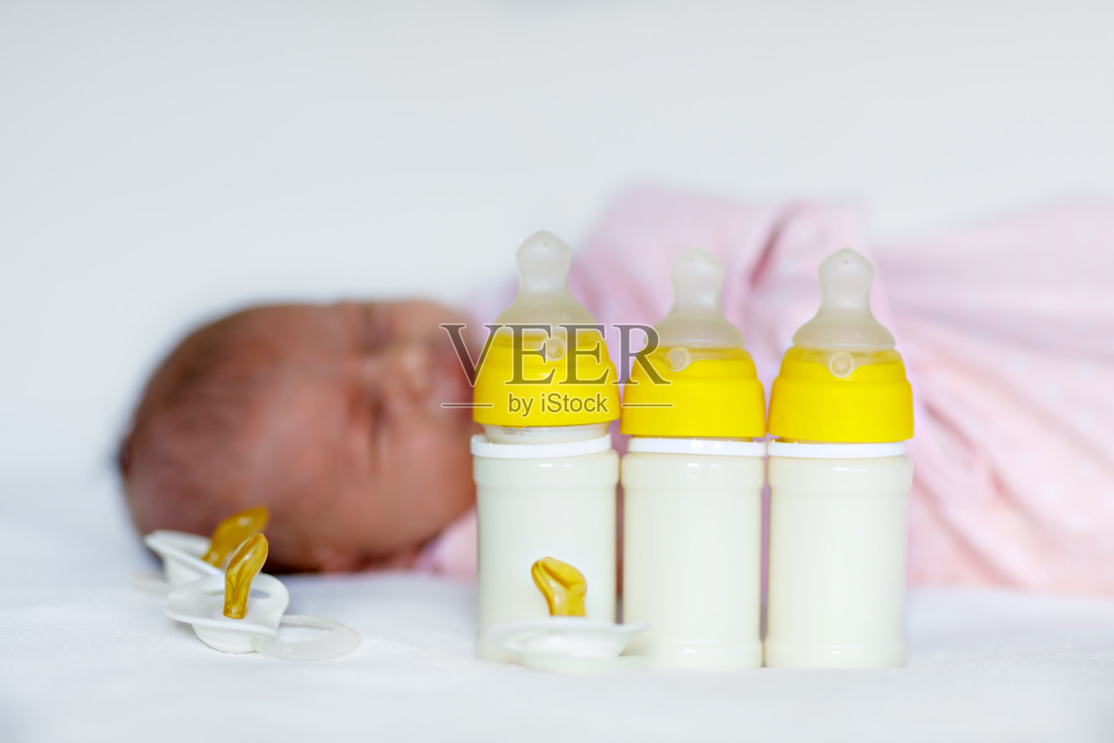 可爱的新生女婴用奶瓶和奶嘴照片摄影图片