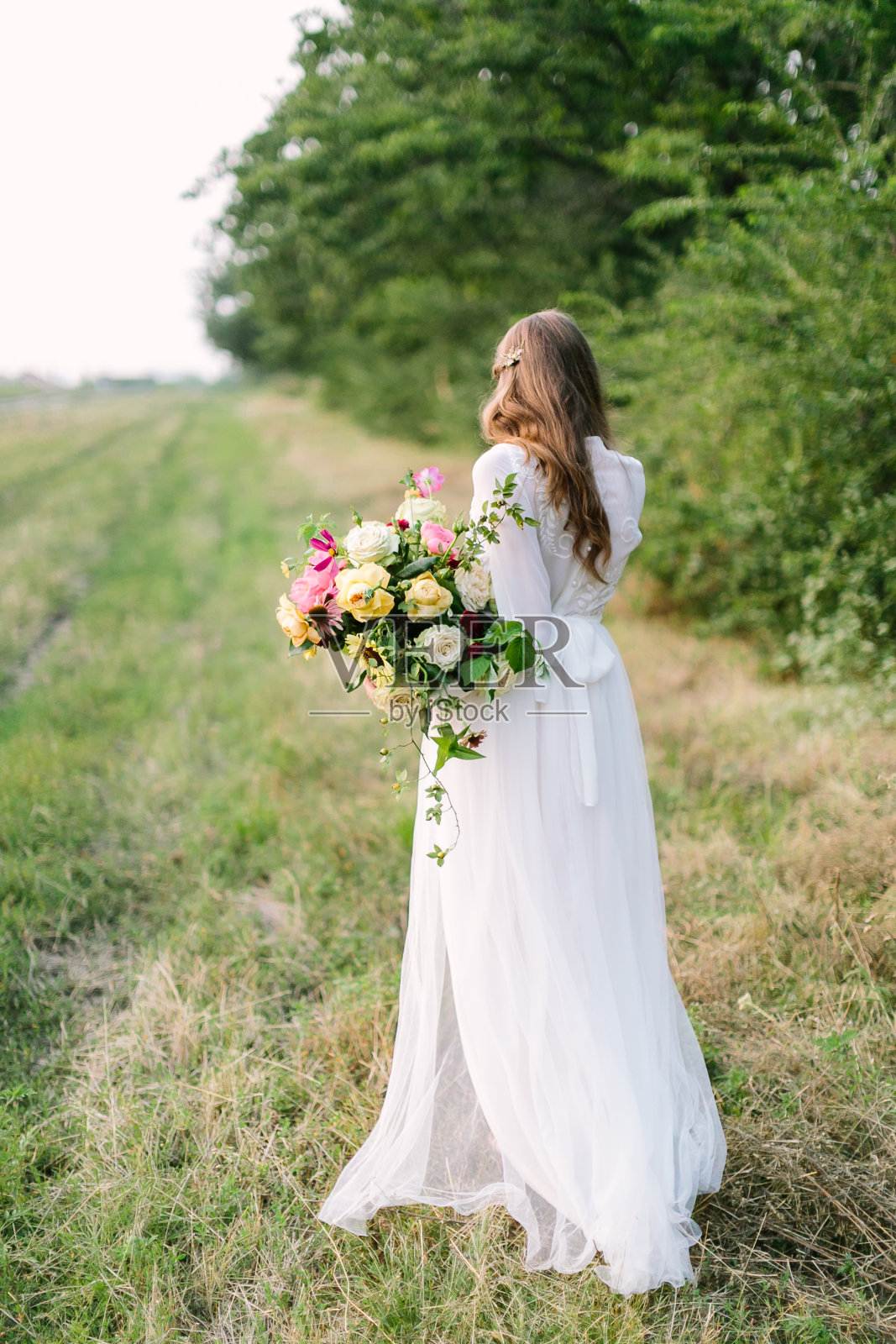 婚礼，婚姻，美丽，自然，花卉设计，乡村生活概念-温柔的剪影年轻的新娘穿着雪白的裙子，飘逸的棕色头发和巨大的牡丹和柔软的玫瑰花束照片摄影图片