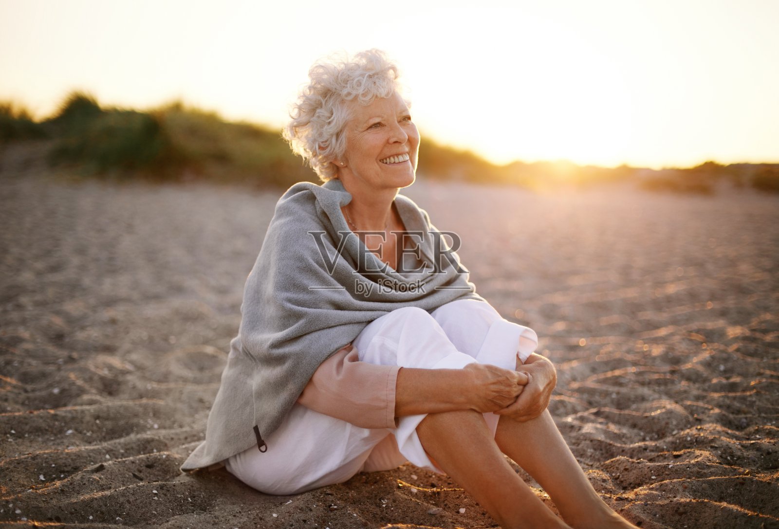 愉快的老妇人坐在海滩上照片摄影图片